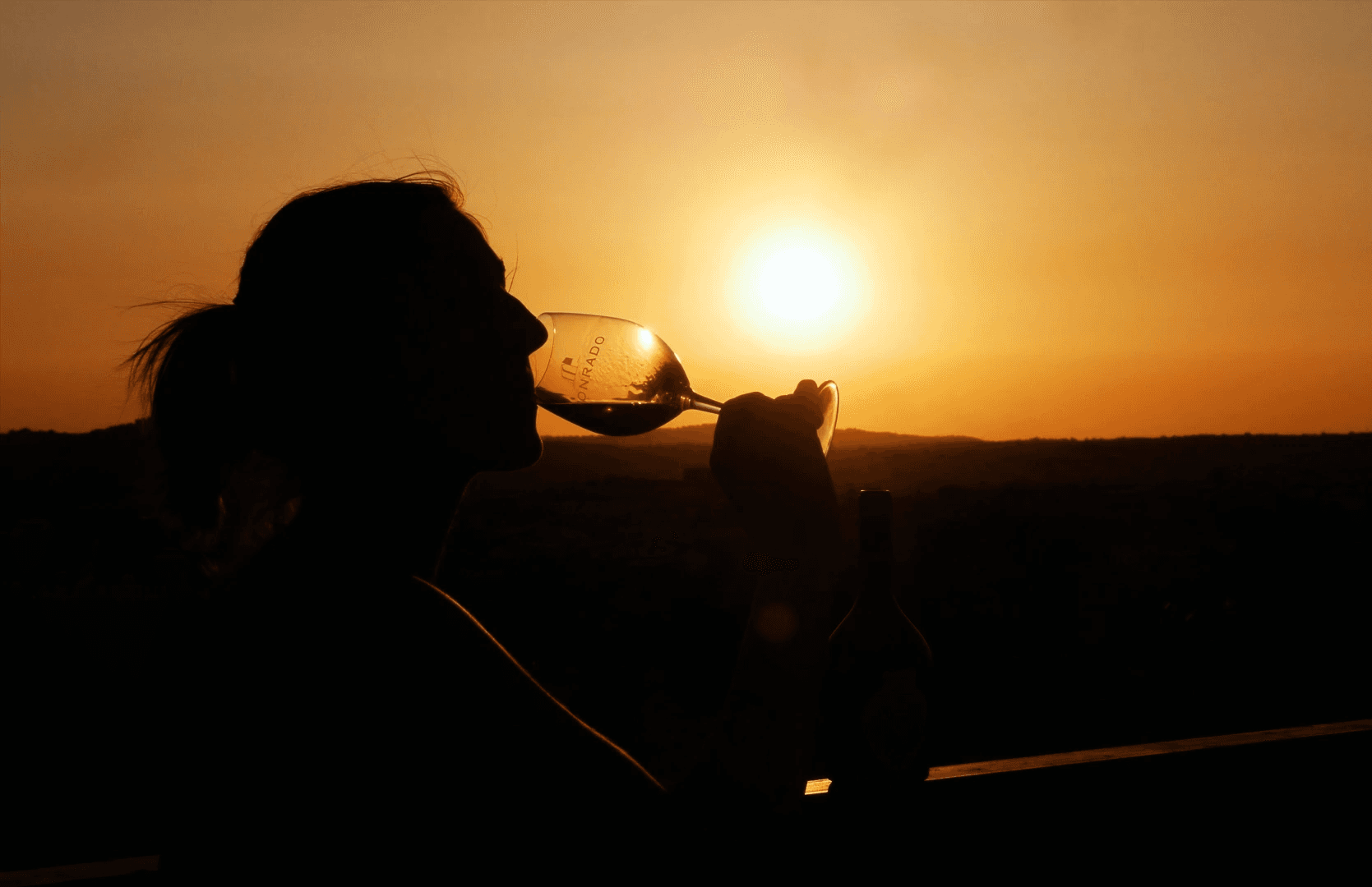 Professional brand photography of a woman drinking Honrado Vineyards wine during a sunset