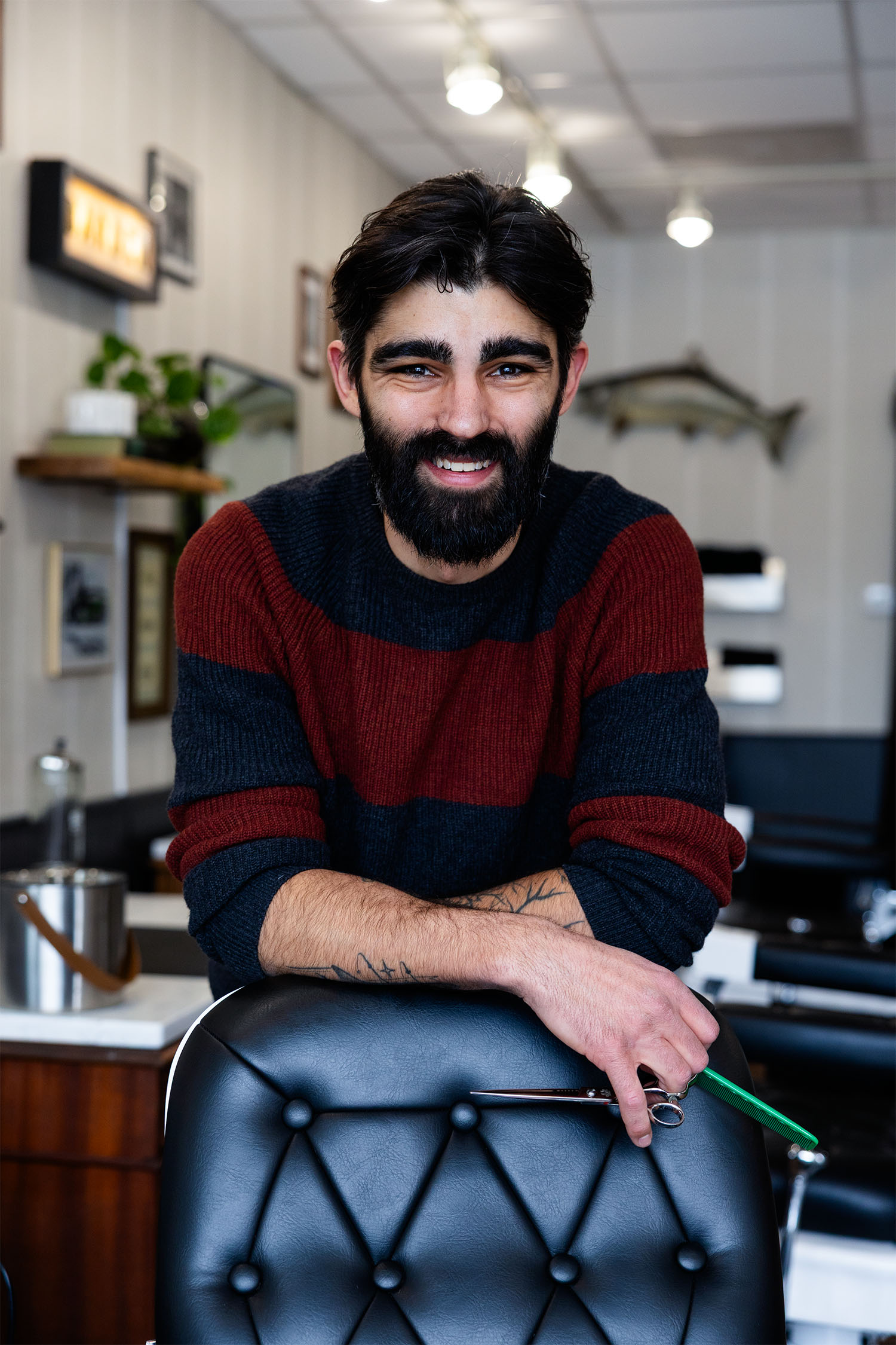 Portrait of Adam Calderone, barber and owner of Calderone’s Barbershop, seated inside the shop