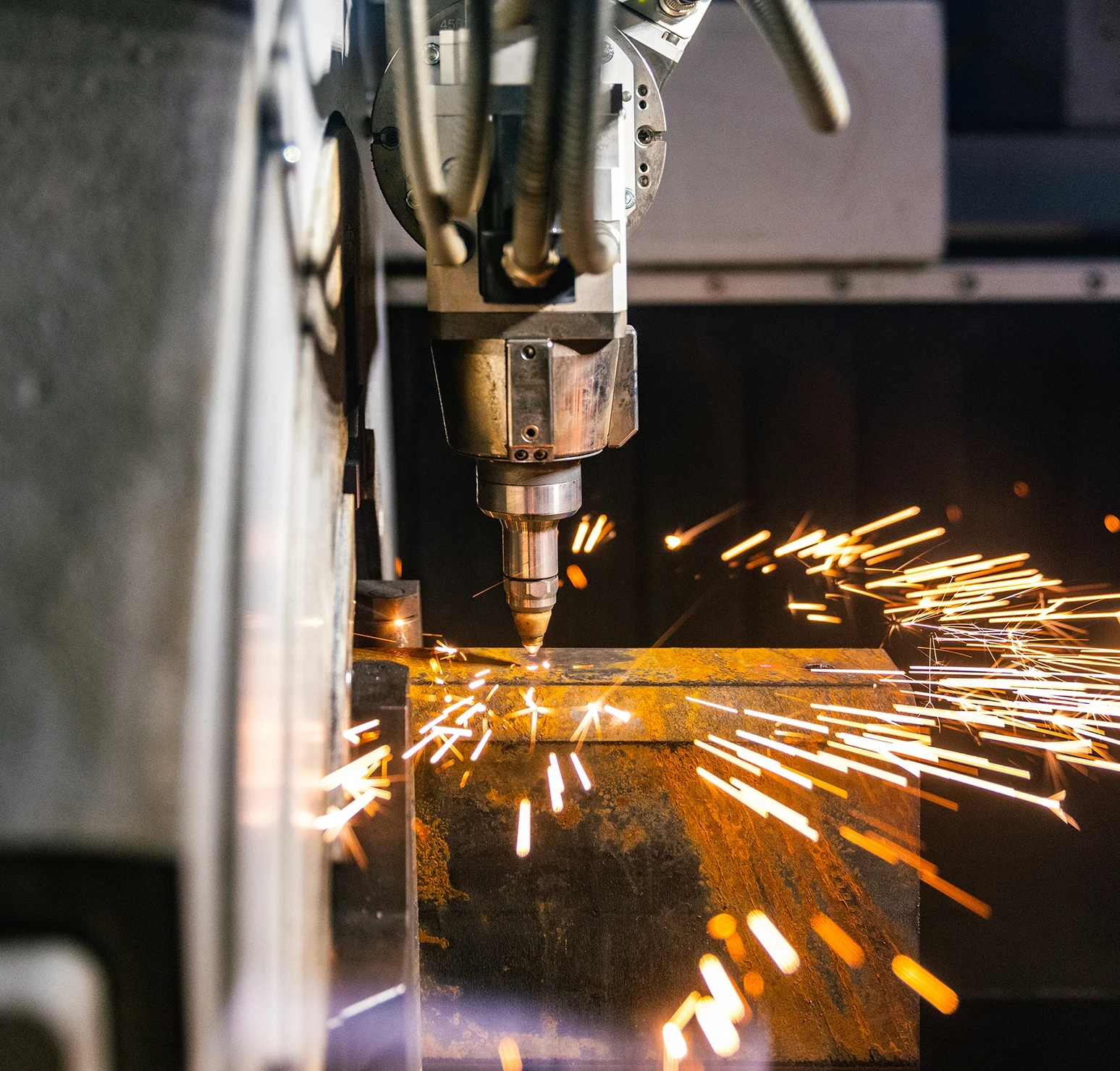 Laser cutting machine cutting a steel tube with visible sparks.