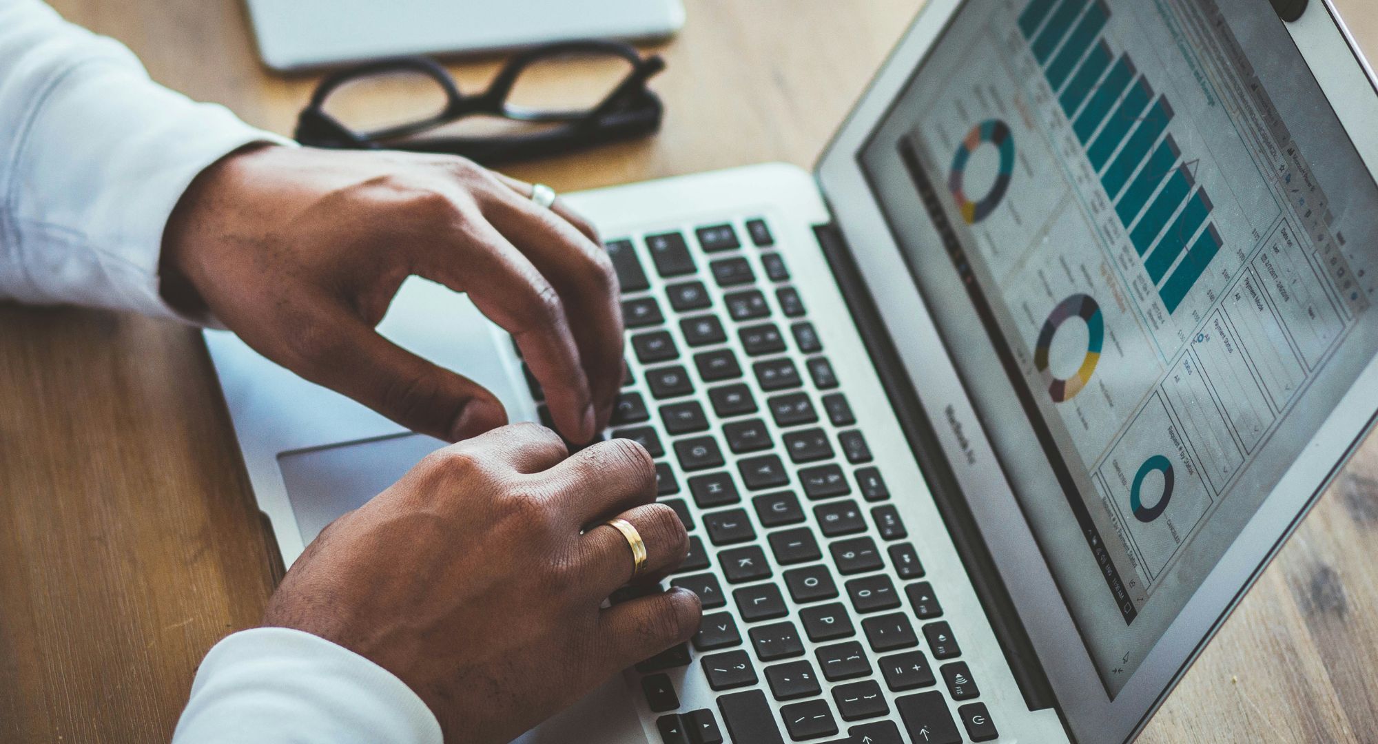 mãos masculinas digitando em um notebook com gráficos na tela