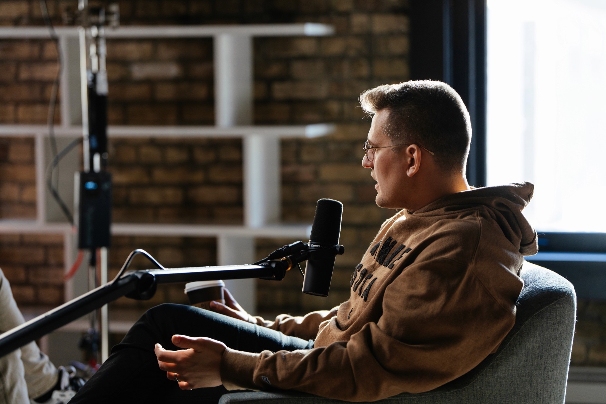 Camera and boom microphone set up for an interview in a brick-walled studio