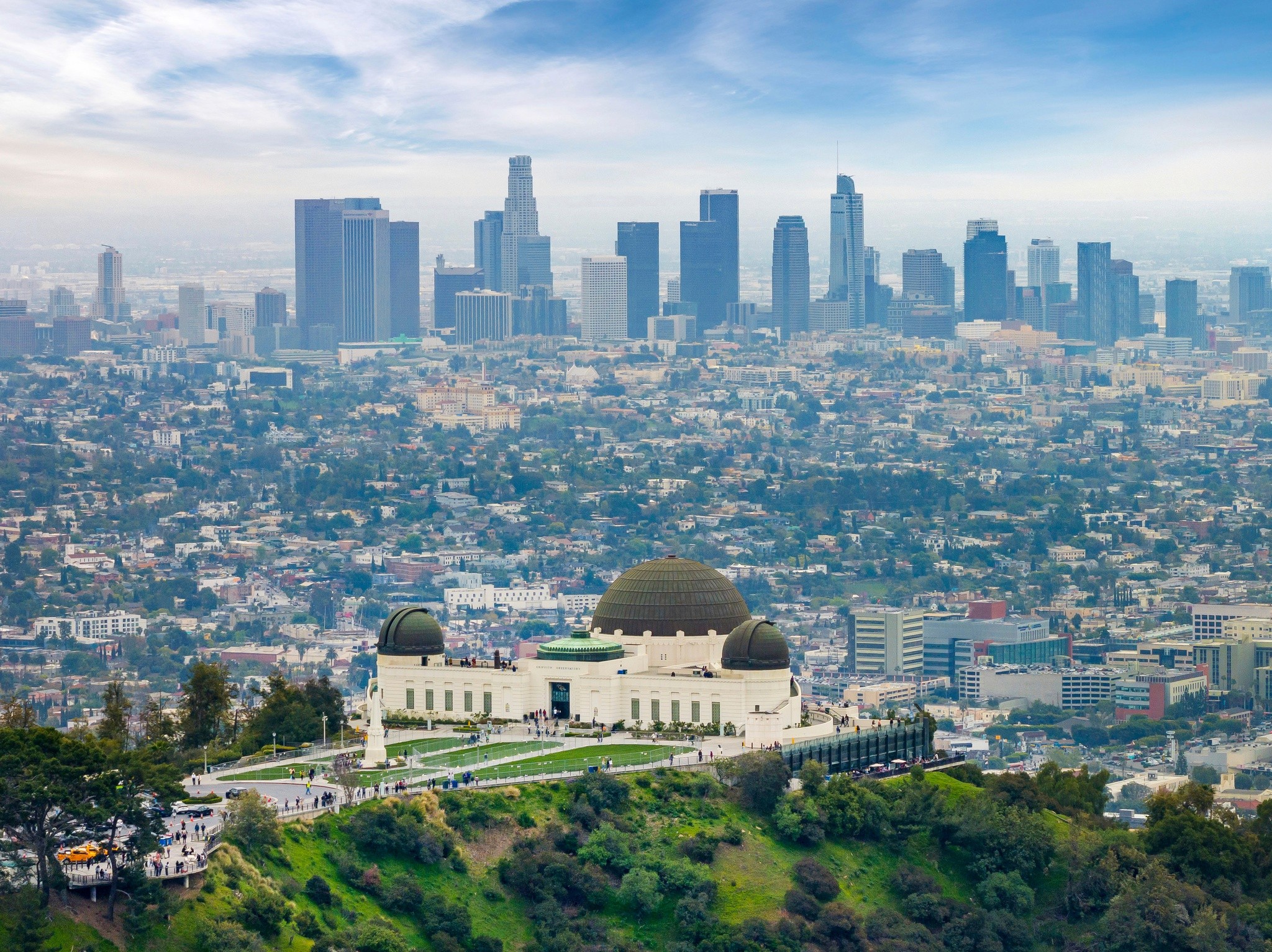 A panoramic view of a city skyline near 4533 ambrose ave, with lush greenery in the foreground and a clear blue sky above.