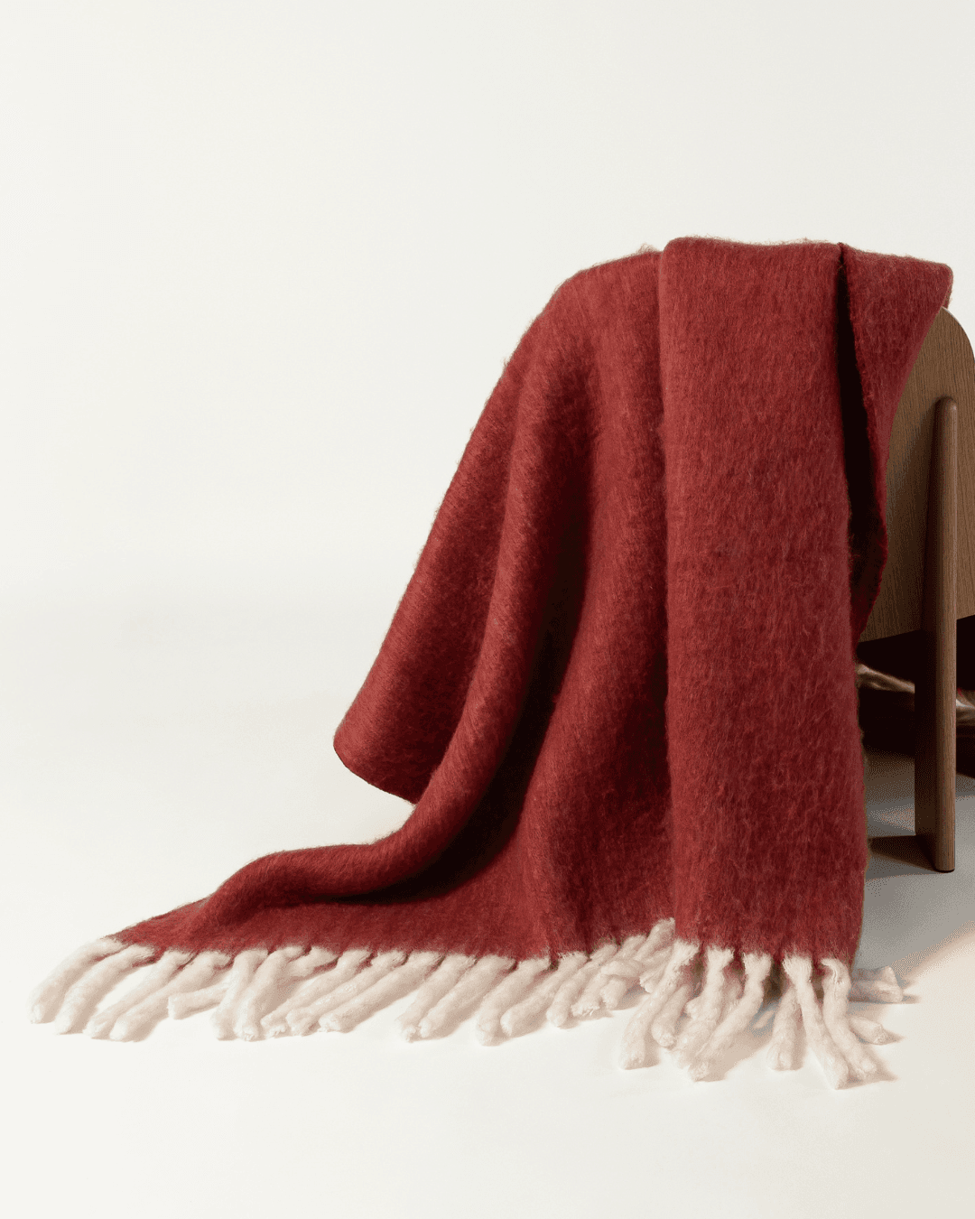 Faux mohair blanket in pomegranate/moon draped on wooden chair