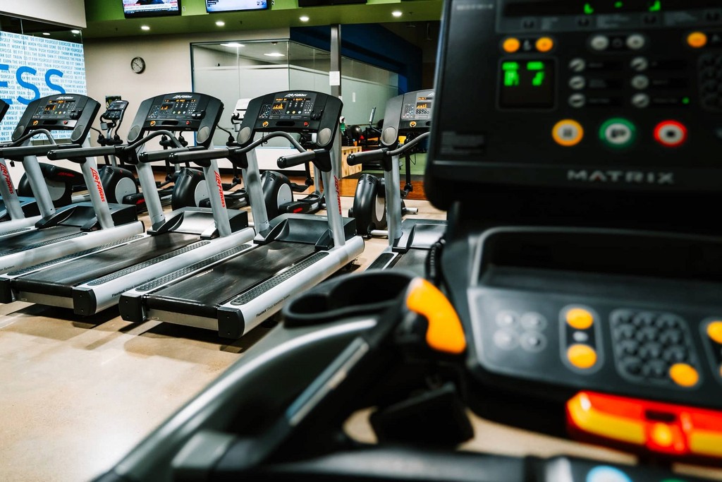 Modern gym with multiple treadmills, fitness equipment, workout facility.