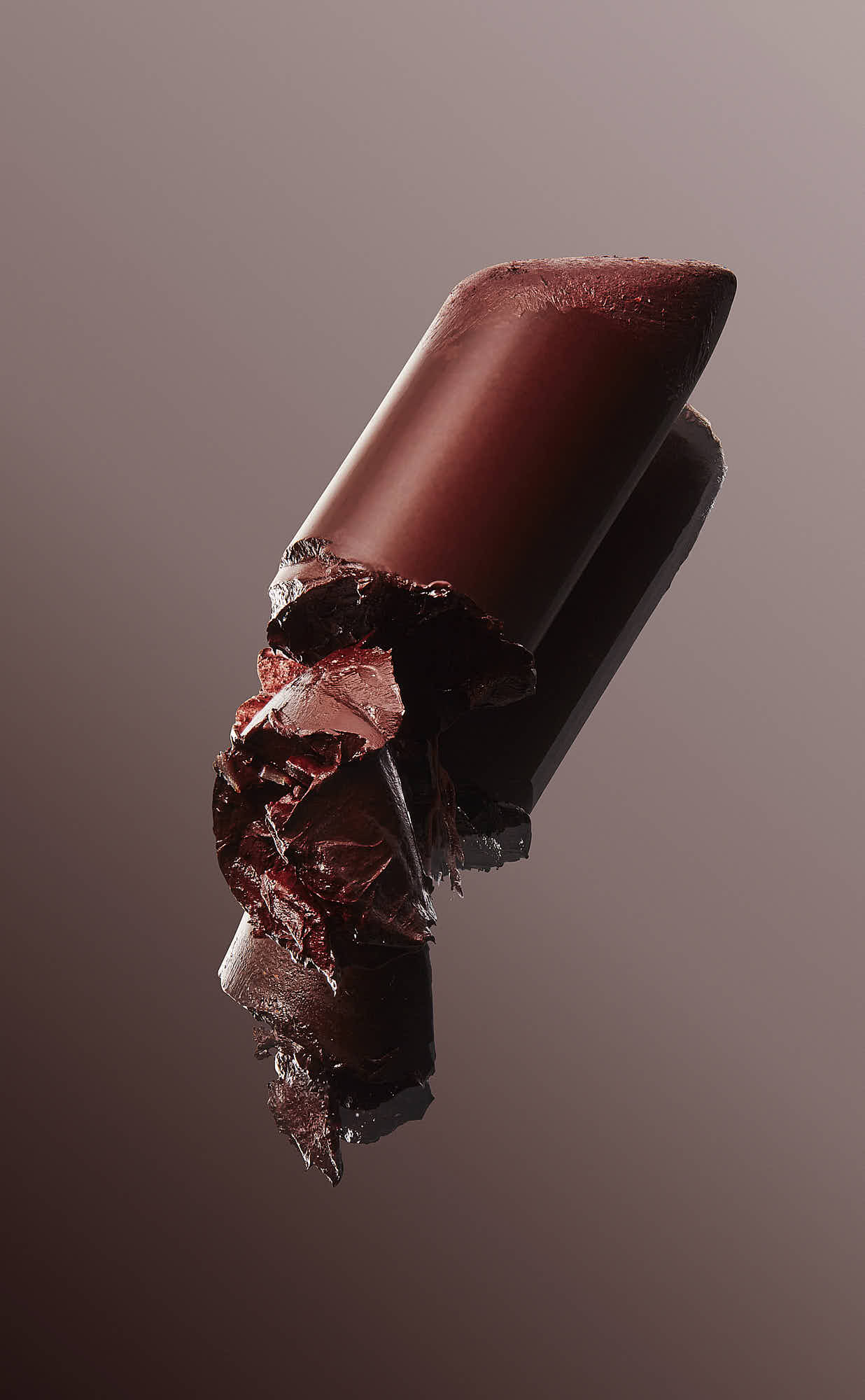 A partially opened lipstick tube with deep red color, resting on a reflective surface.