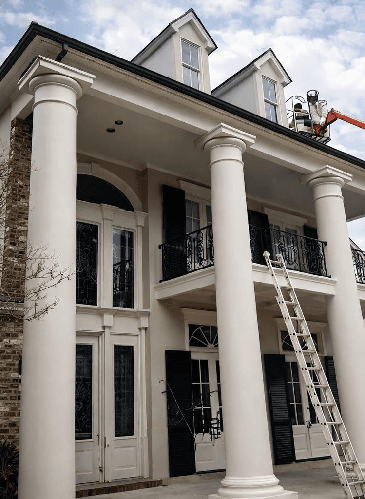 A serene outdoor seating area with two chairs, surrounded by lush greenery and a glassed-in structure.