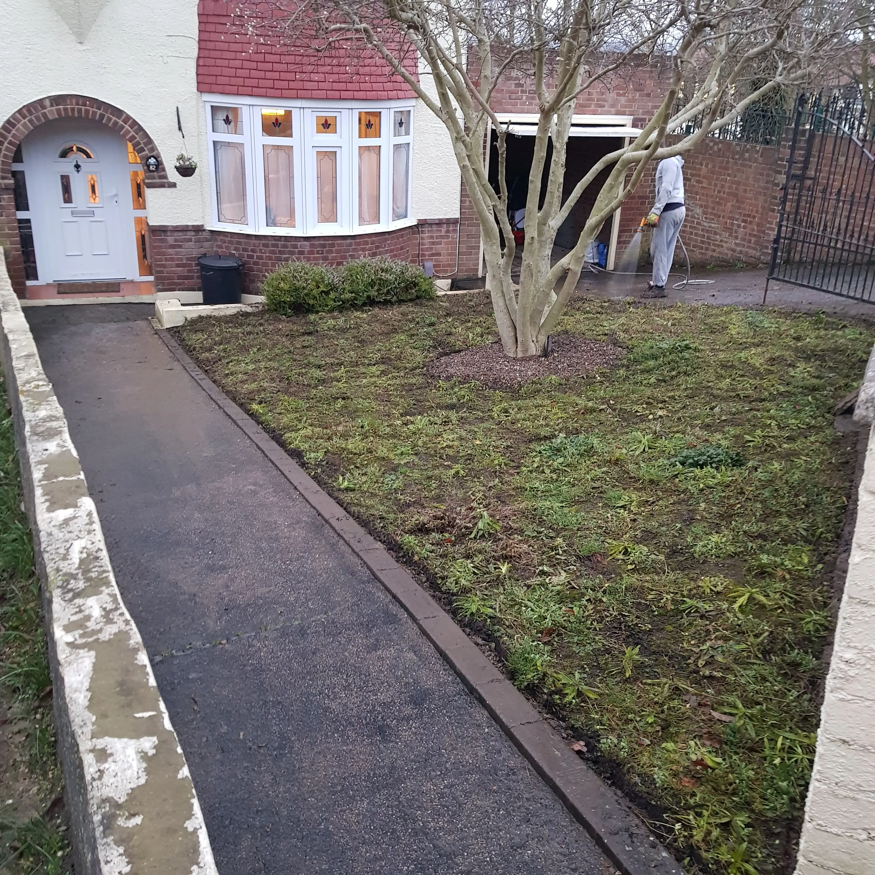 A view of a residential front yard with grass and a pathway leading to the entrance of the house.