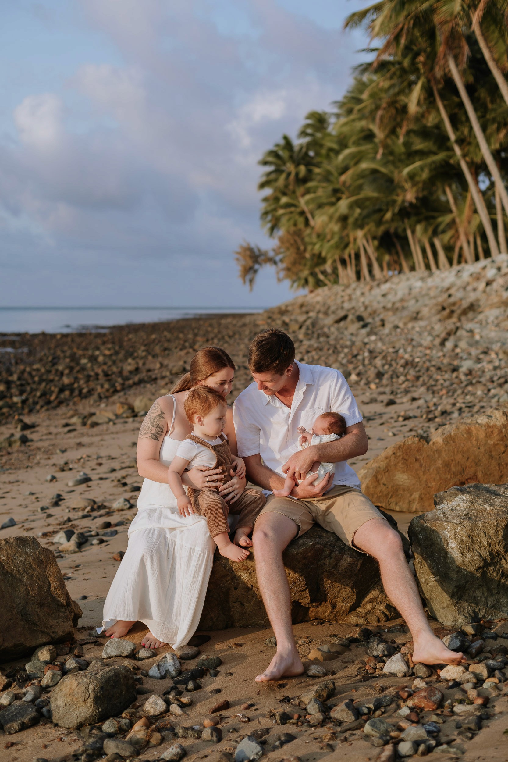 Family sitting on rocks at a family photography session in Mackay