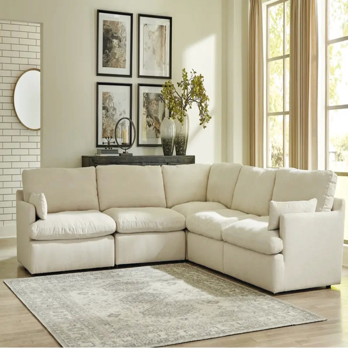 Tanavi 5-Piece Modular Sofa in a neutral-toned living room, with a rug, wall art, & large windows with beige curtains