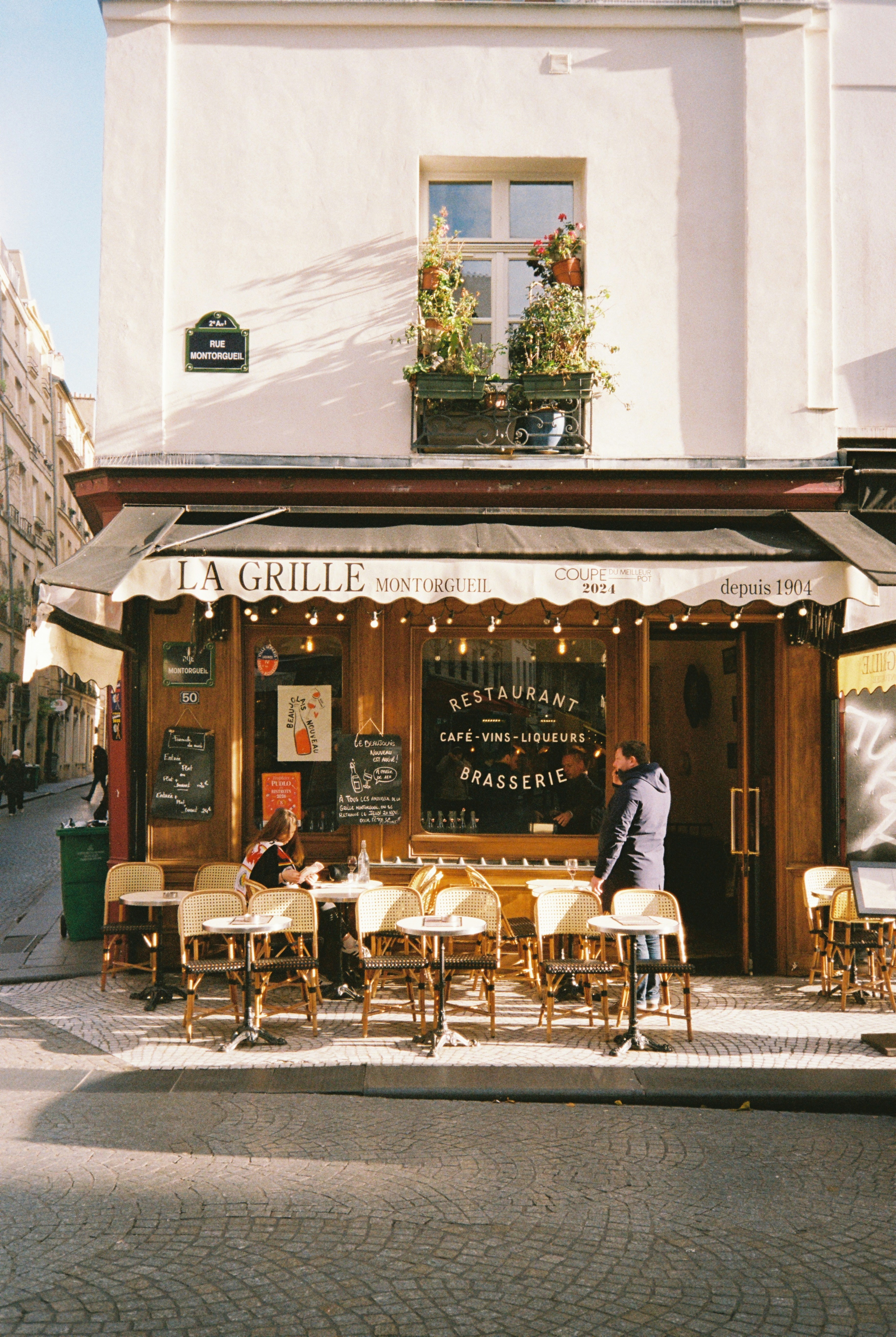 People sit at tables outside a parisian restaurant.