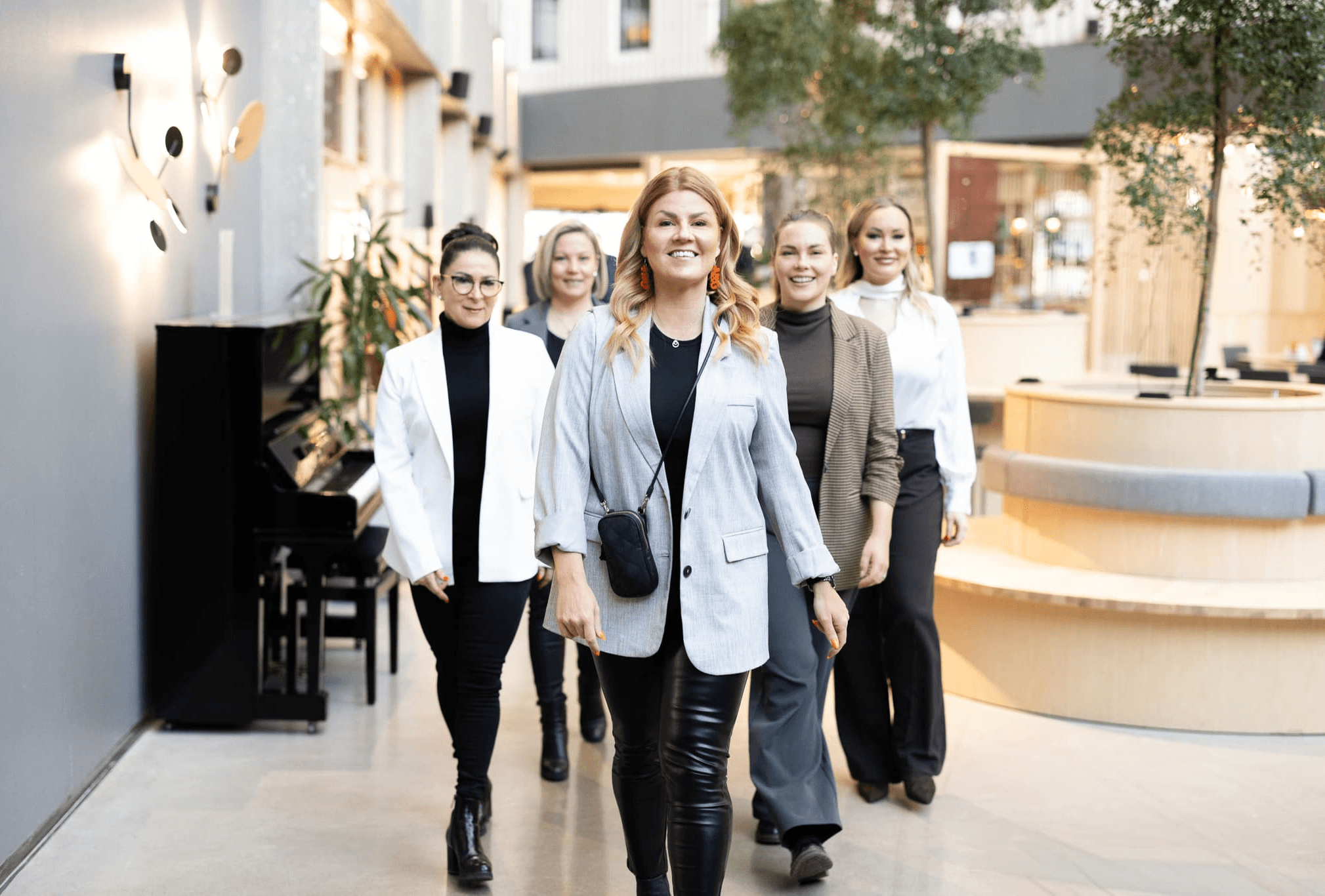 Kaksi esiintyjää oransseissa asuissa esittelee “Syventävät myyntivalmennukset” – modernin B2B-myynnin tekniikat ja prosessit; diat suurilla näytöillä, yleisö pöytien ääressä.