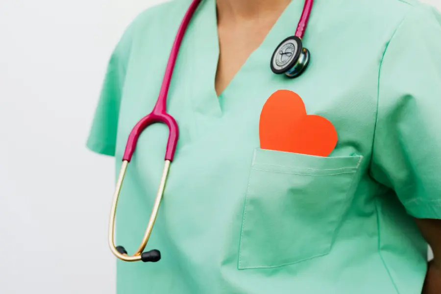 Close-up of a nurse in green scrubs with a pink stethoscope and red heart in pocket symbolizing compassionate AI medical consultant software.