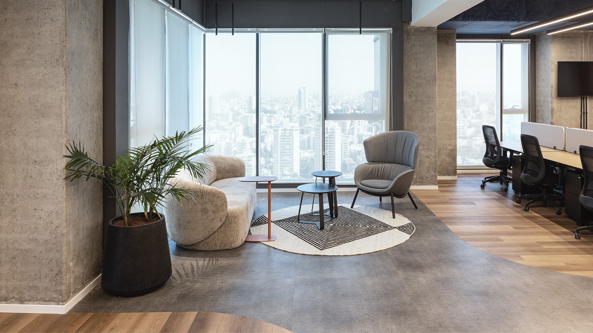 פינת ישיבה מול הנוף: אזור לאונג' אינטימי עם כורסה וספה מעוגלת (Curved Sofa) לצד קיר המסך, המאפשרים רגעים של שקט והשראה מול הנוף האורבני.