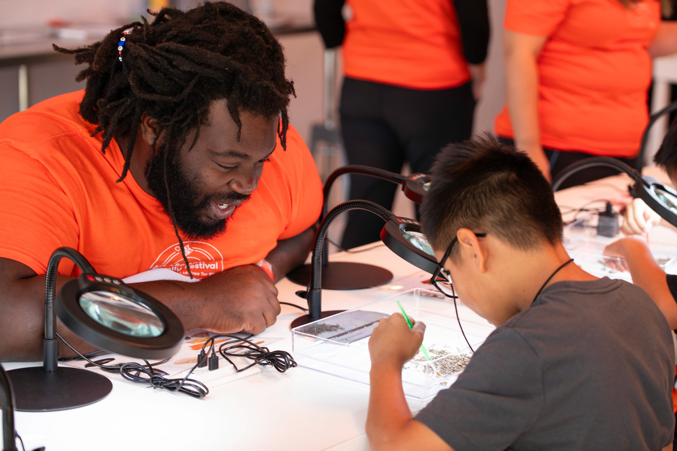An event staff member managing a hands-on fossil dig activity for children.
