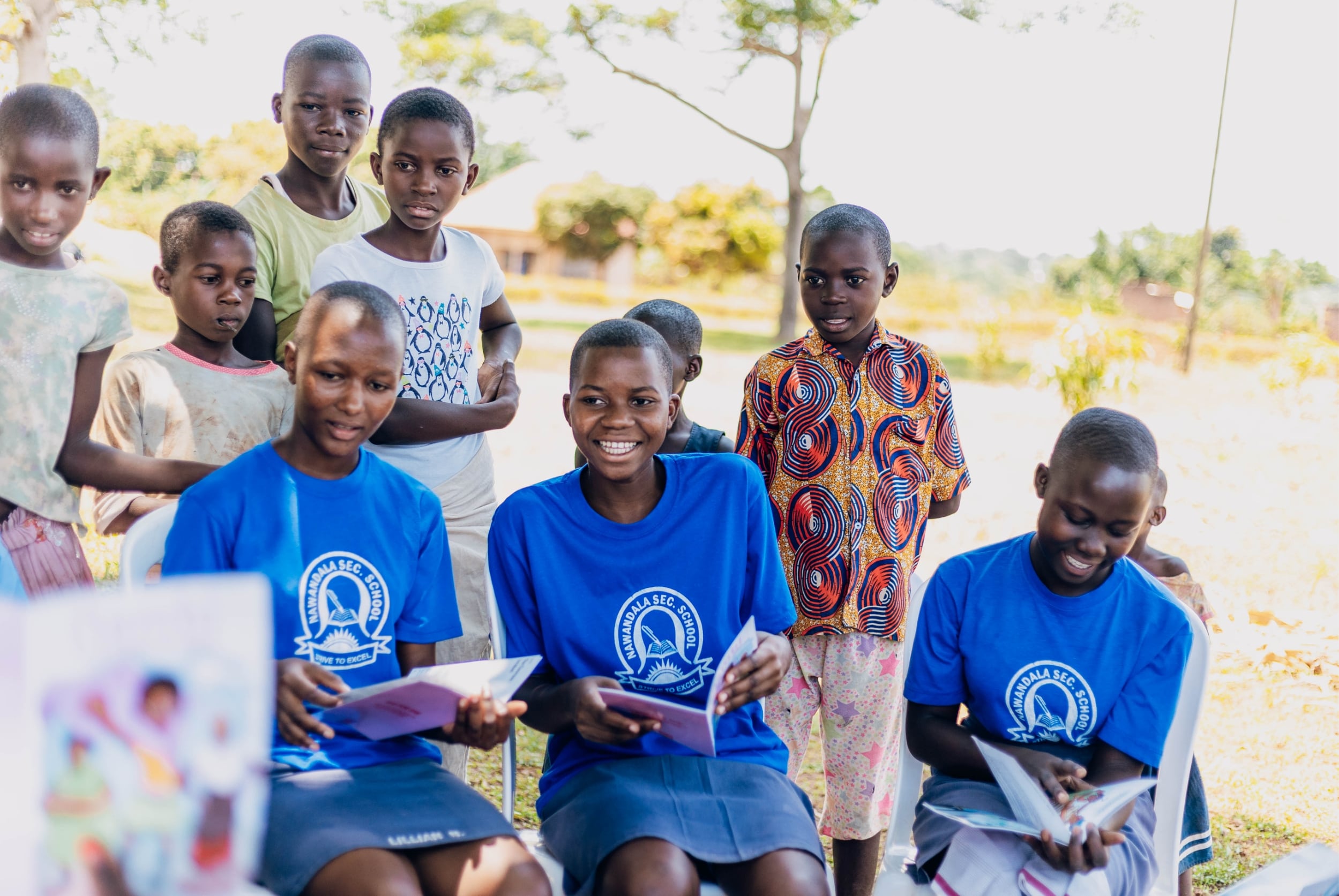Girls smiling while holding an educational book created by She For She