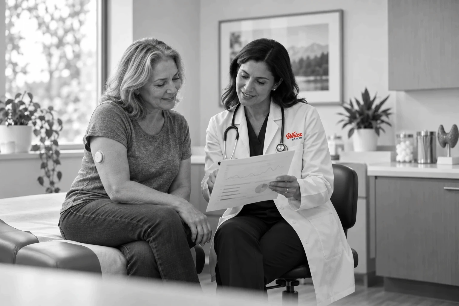 Endocrinologist reviewing glucose monitor results with a patient wearing a continuous glucose monitor