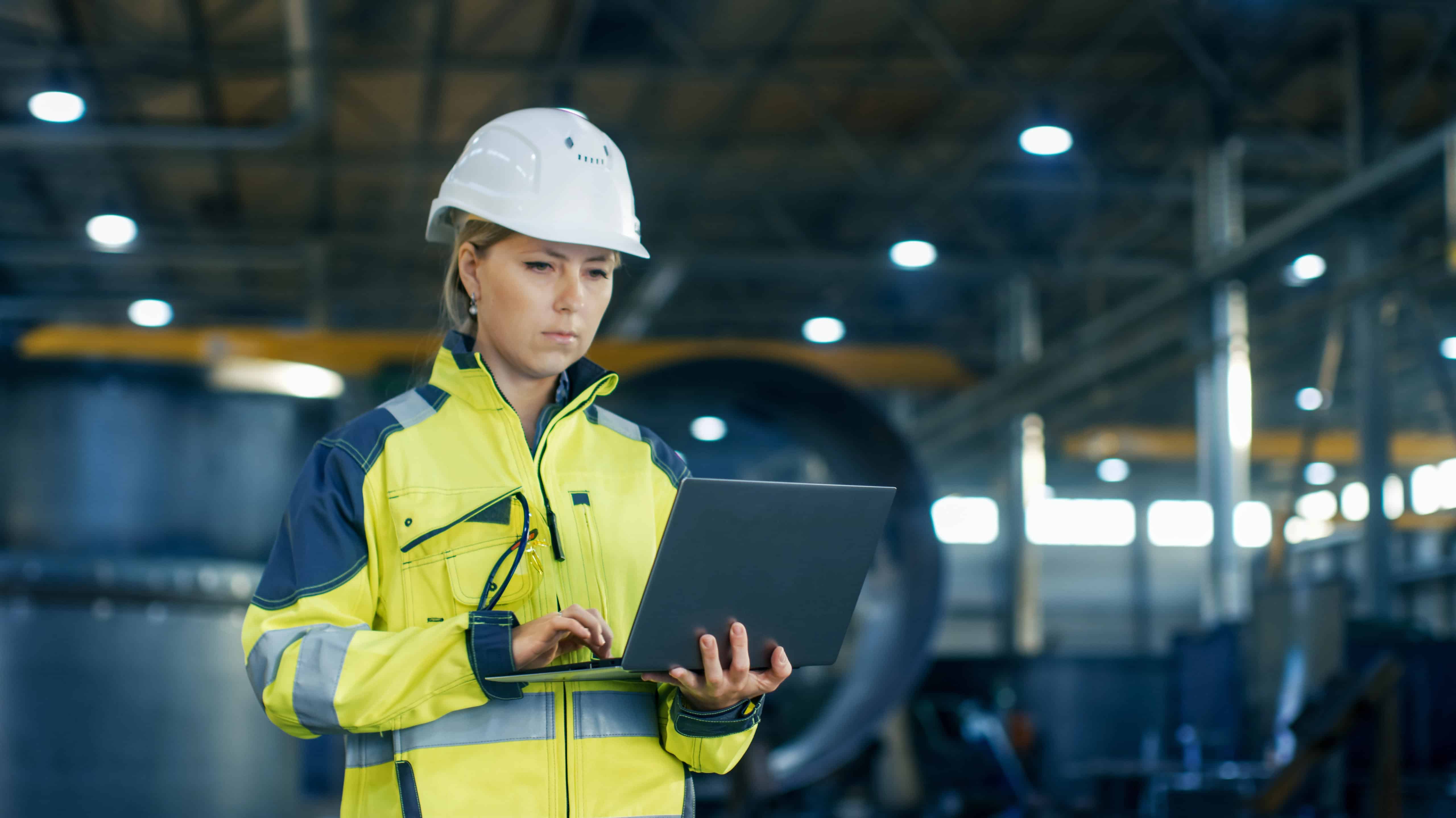 Female engineer in high-vis safety clothing performing checks on equipment