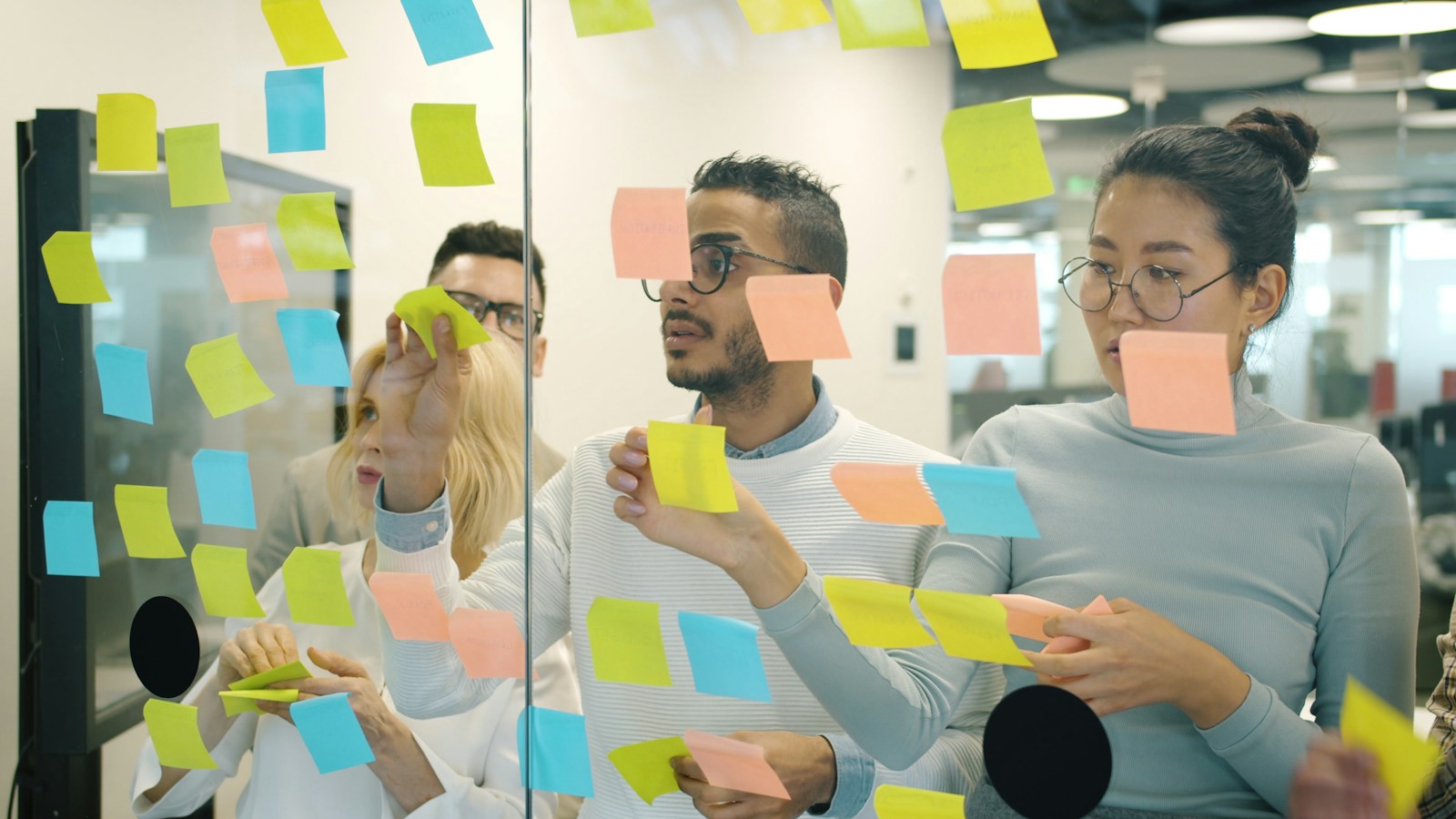 Team mapping a long-tail content cluster with colorful notes on a glass wall