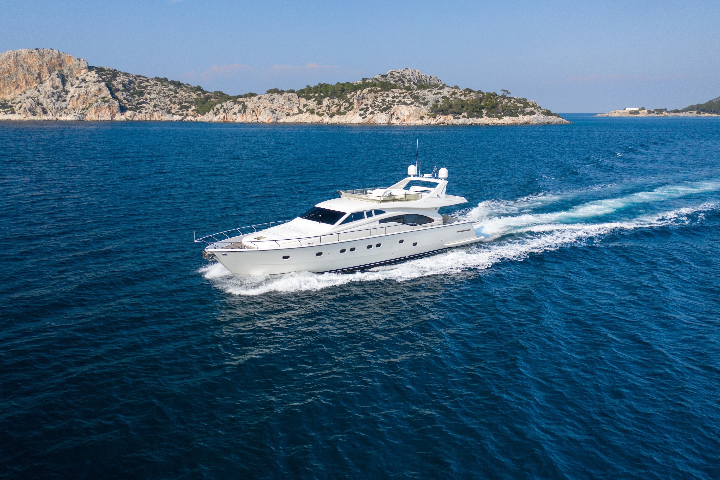 White Ferretti 68 yacht bow deck with teak flooring and safety railings, cruising through calm blue waters near Greek islands.