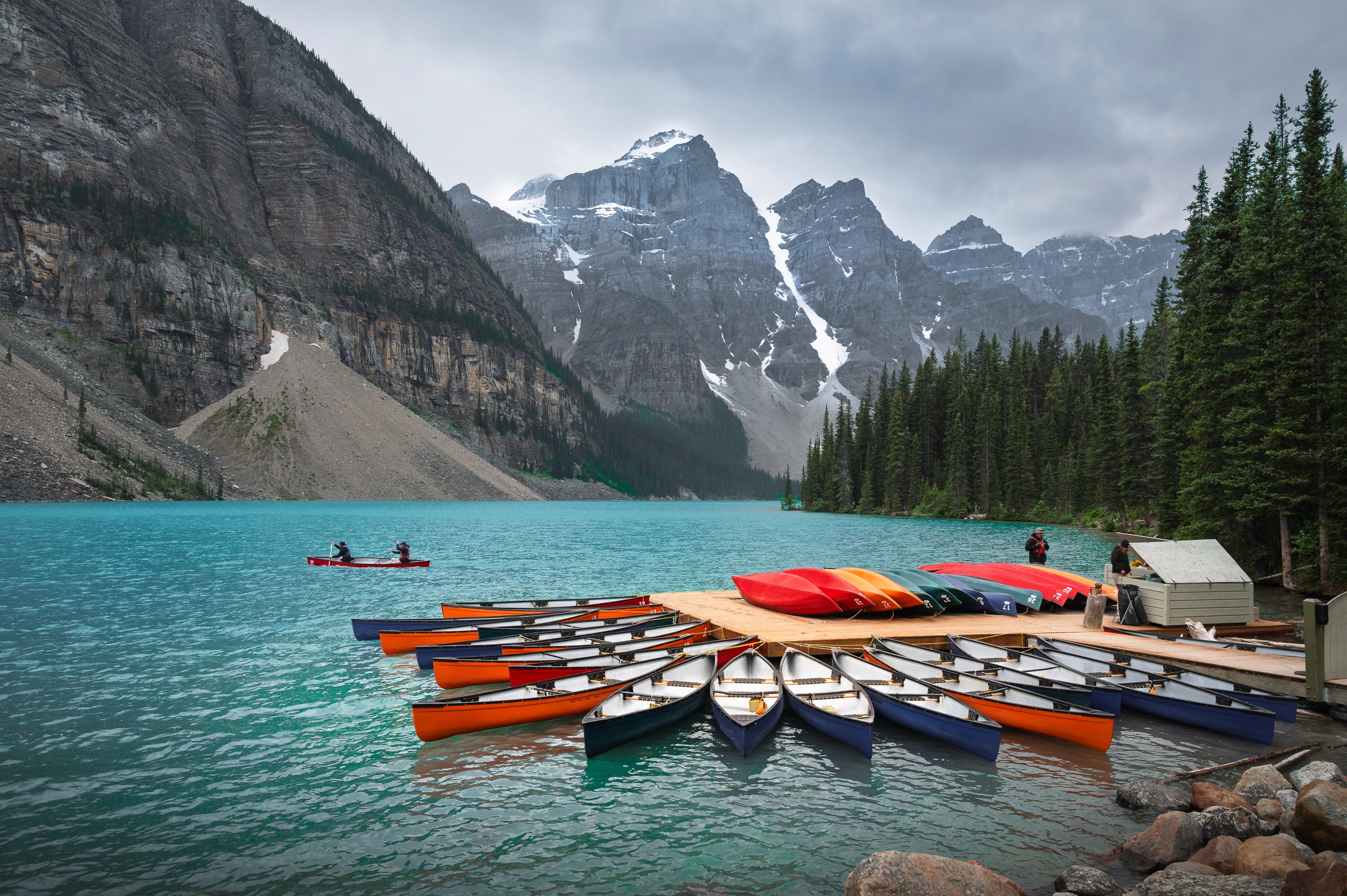 Colorful kayaks showcase the foreground of beautiful Moraine Lake in Banff, Alberta, Canada