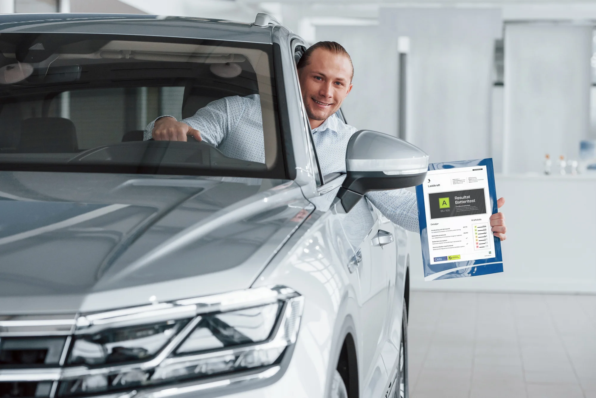 Person vid en svart elbil i bilhall, med en batteritest-rapport synlig på framrutan.