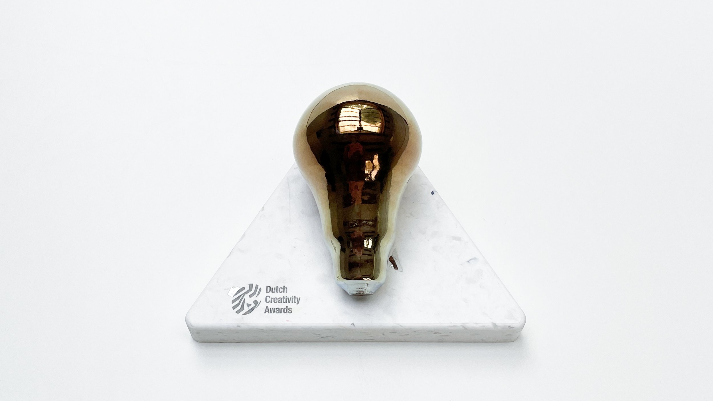 Image of the golden glass award placed on a recycled plastic award base