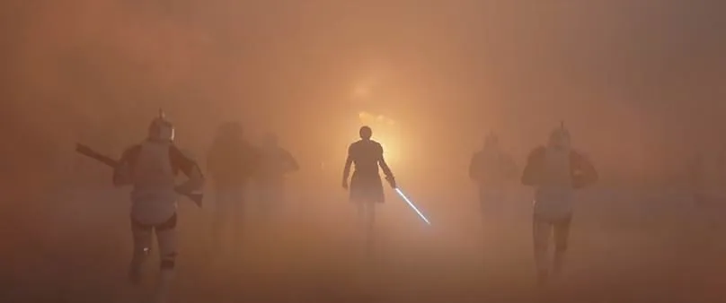 A burning battlefield with Anakin Skywalker holding a blue lightsaber leading an army of Clone Troopers