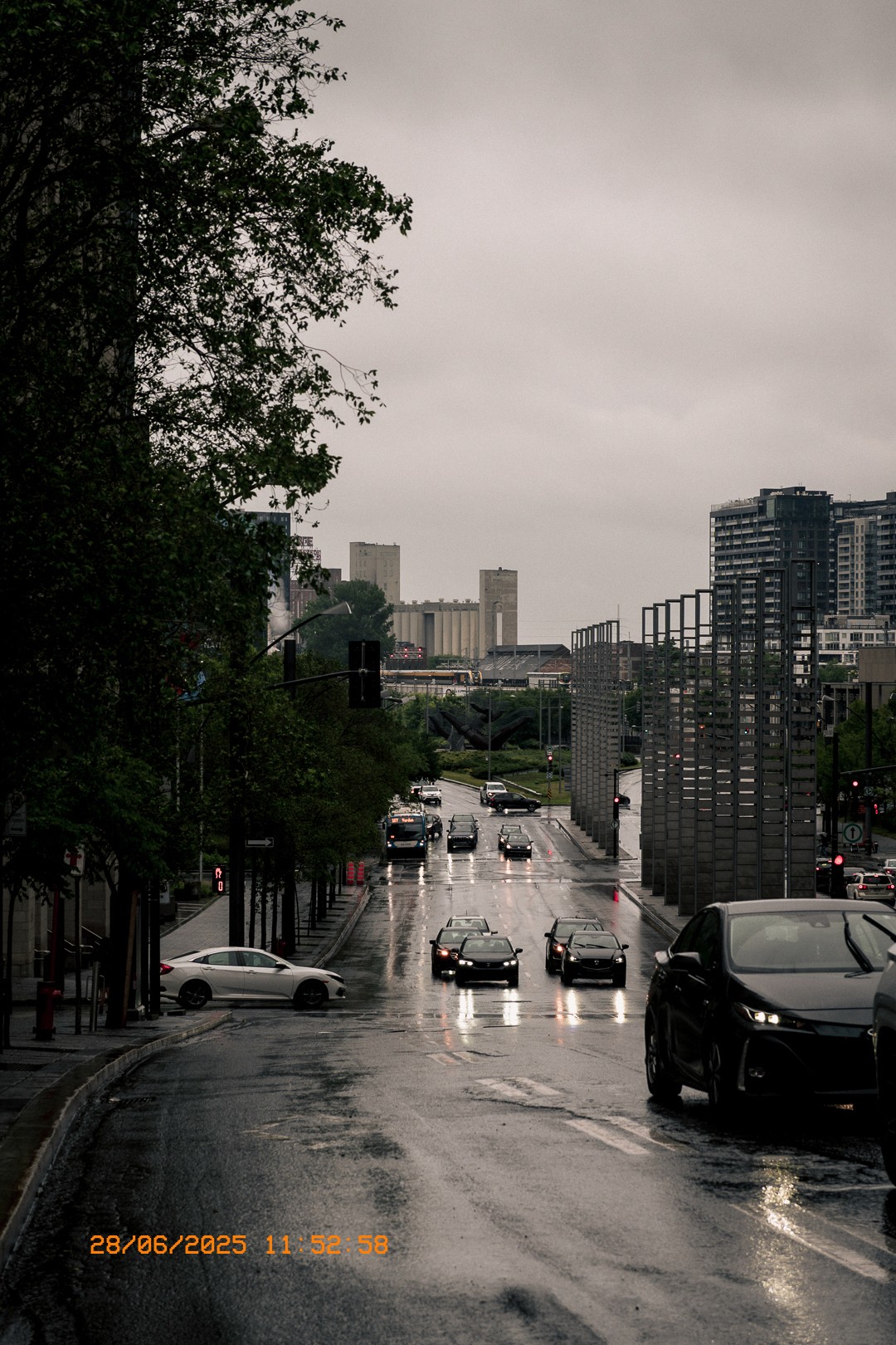 Scène urbaine grise à Montréal par temps pluvieux, circulation active.