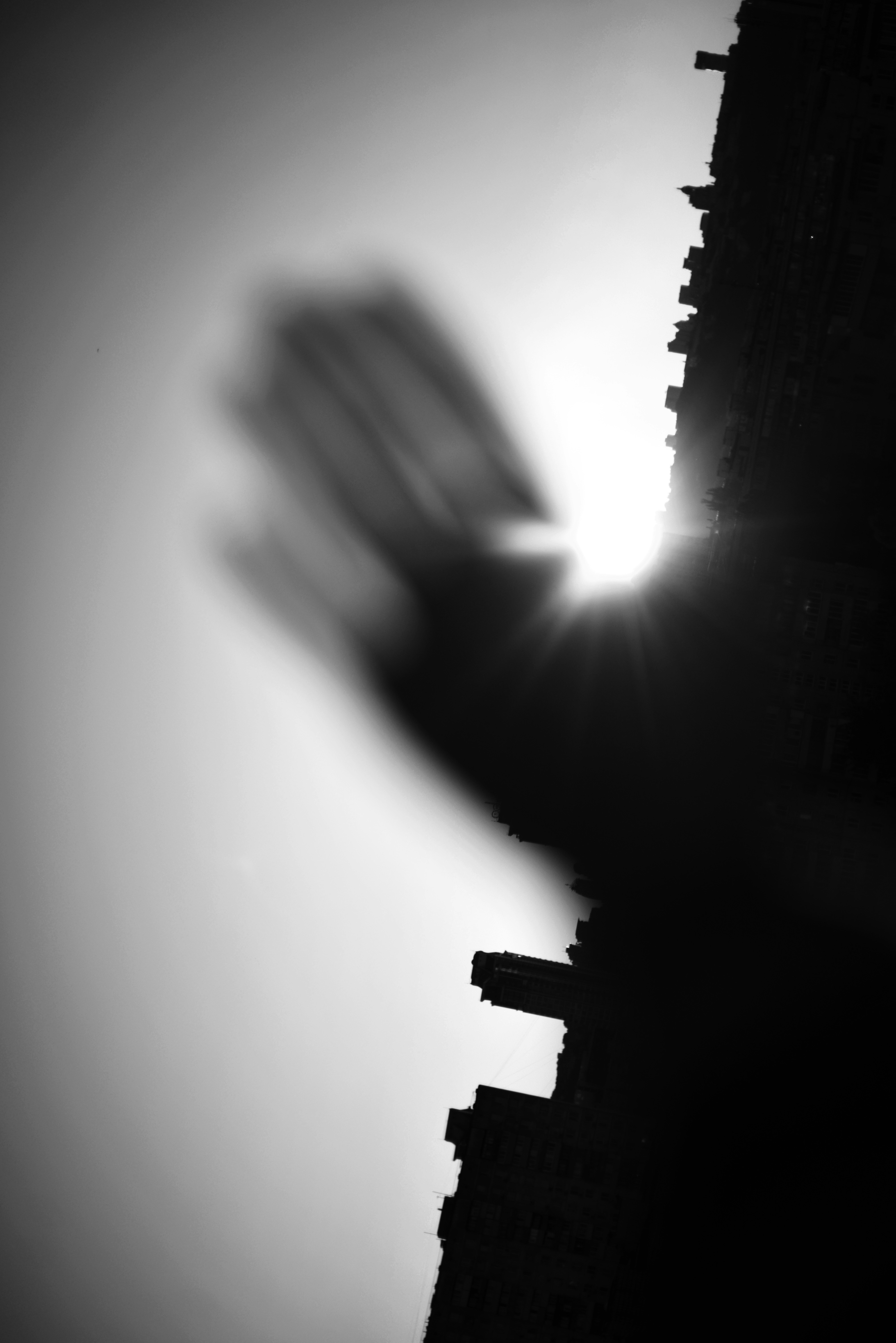 Silhouette of a hand reaching towards the sun.
