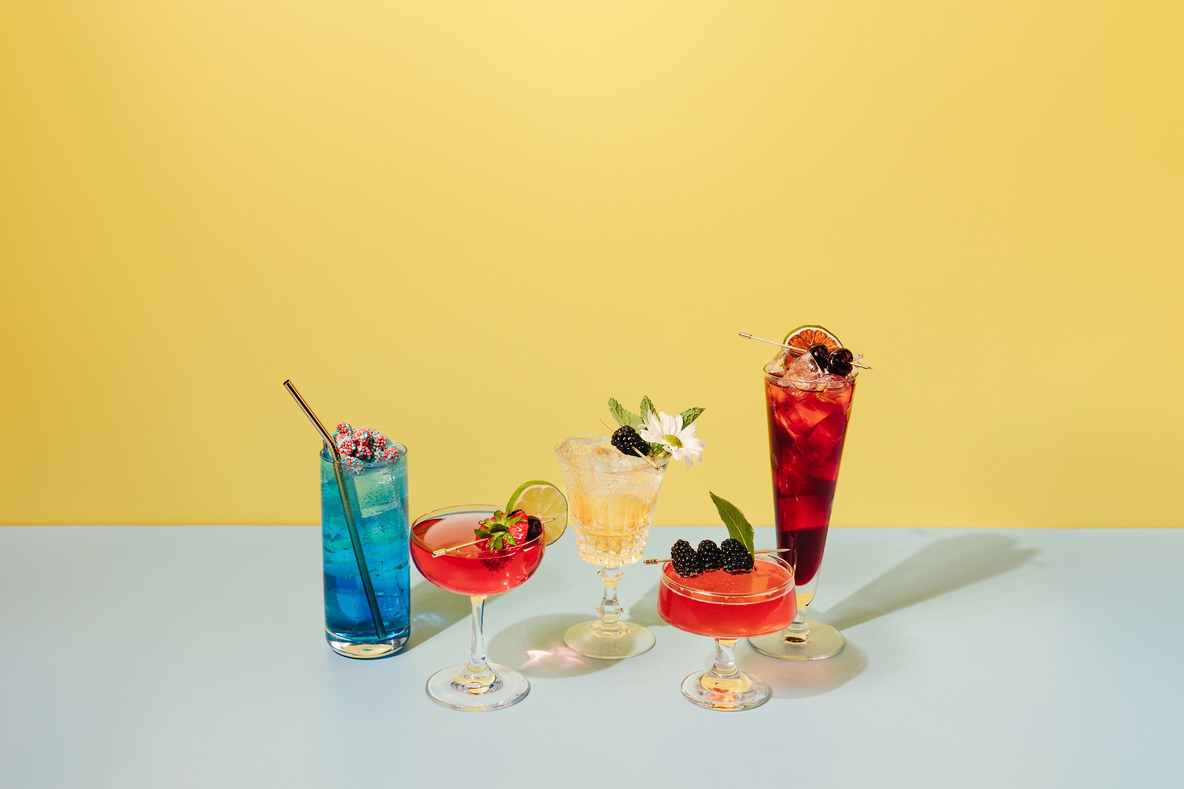 Lineup of So Curious Co's mocktails on a bright yellow background