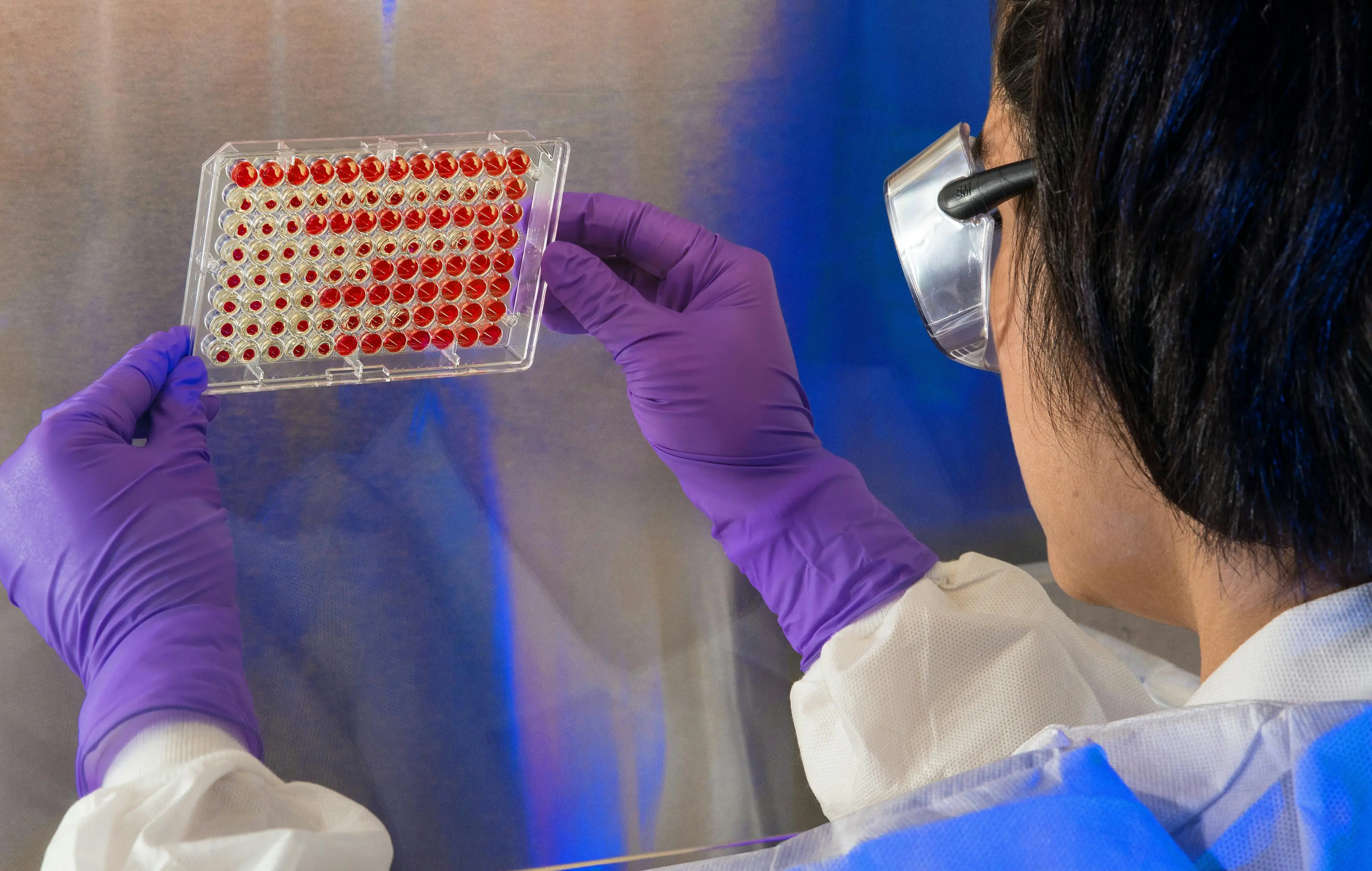 woman in a lab holds up samples. She's doing science research in high school