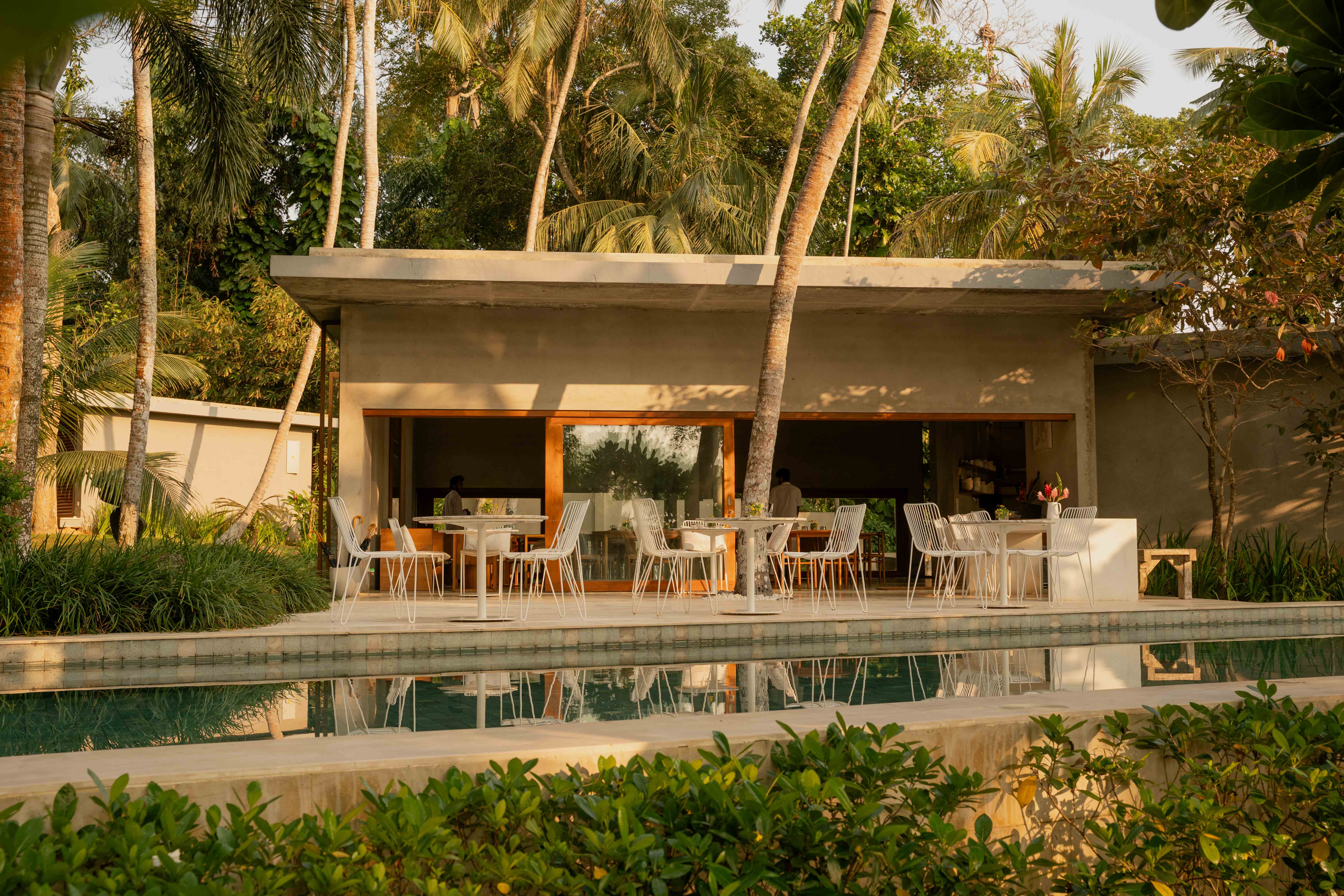 Restaurant of a boutique hotel surrounded by palmtrees at golden hour