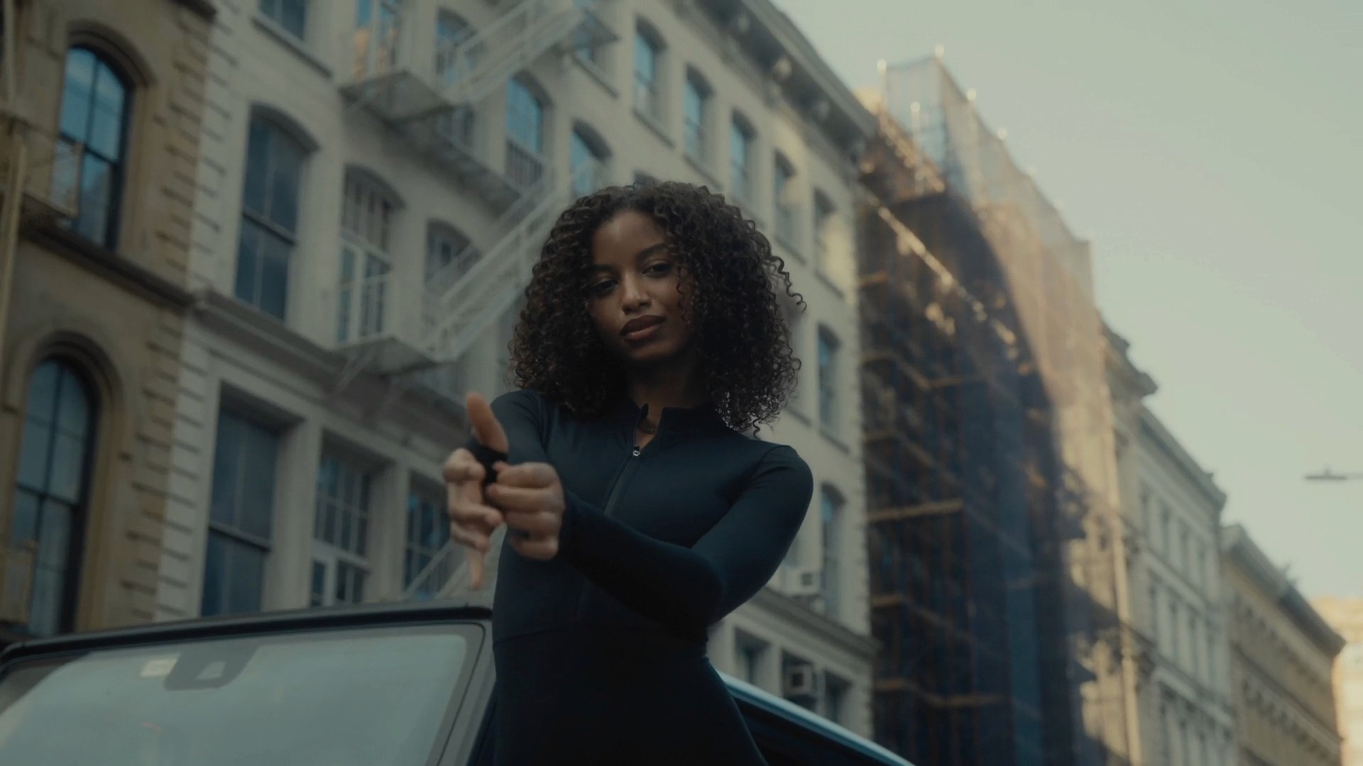 A model posing confidently on a city street, with skyscrapers and urban architecture surrounding her
