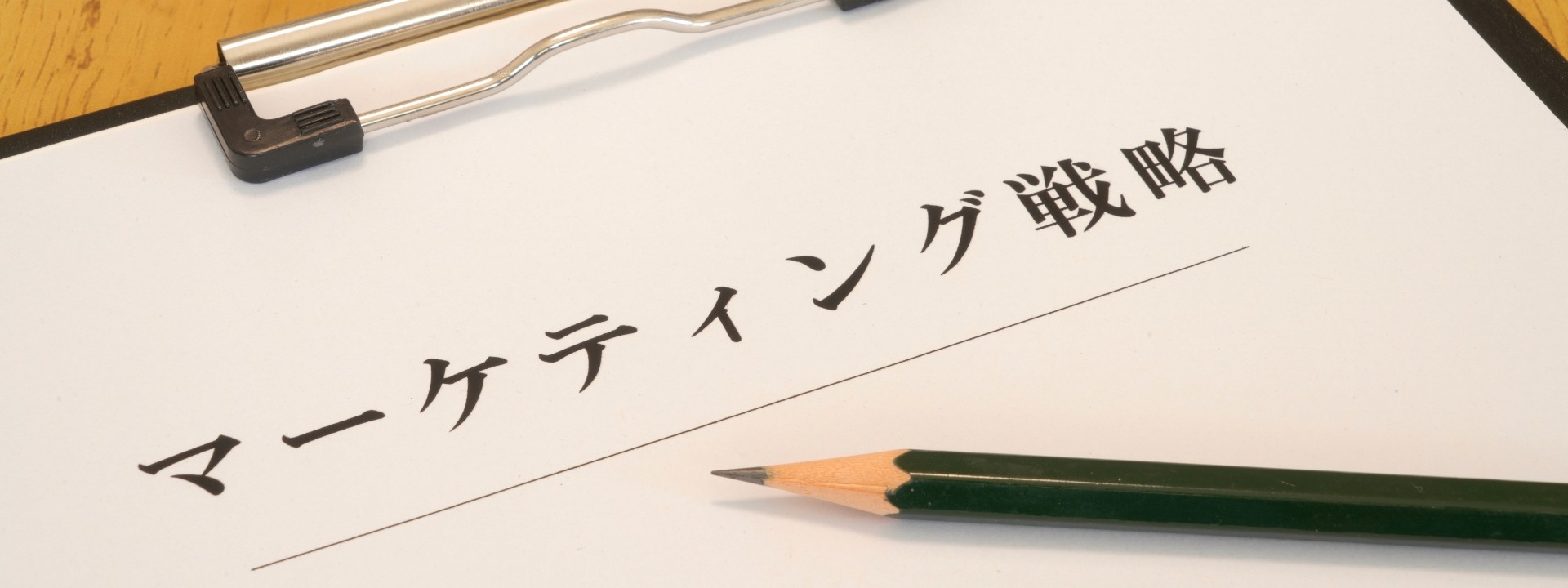 マーケティング戦略と書かれたバインダーとペンの画像