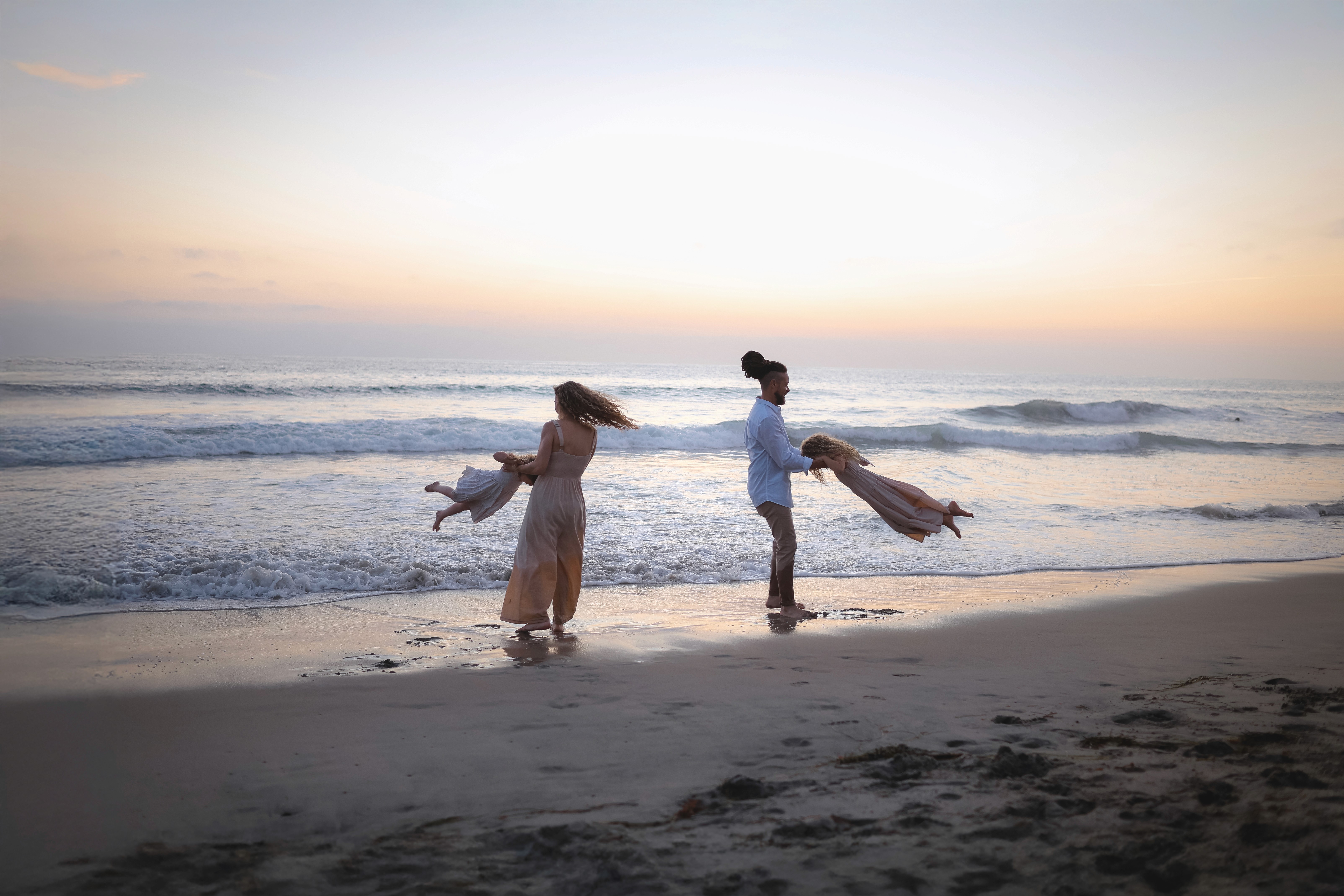 Family plying along the shoreline during a candid family beach session in San Diego