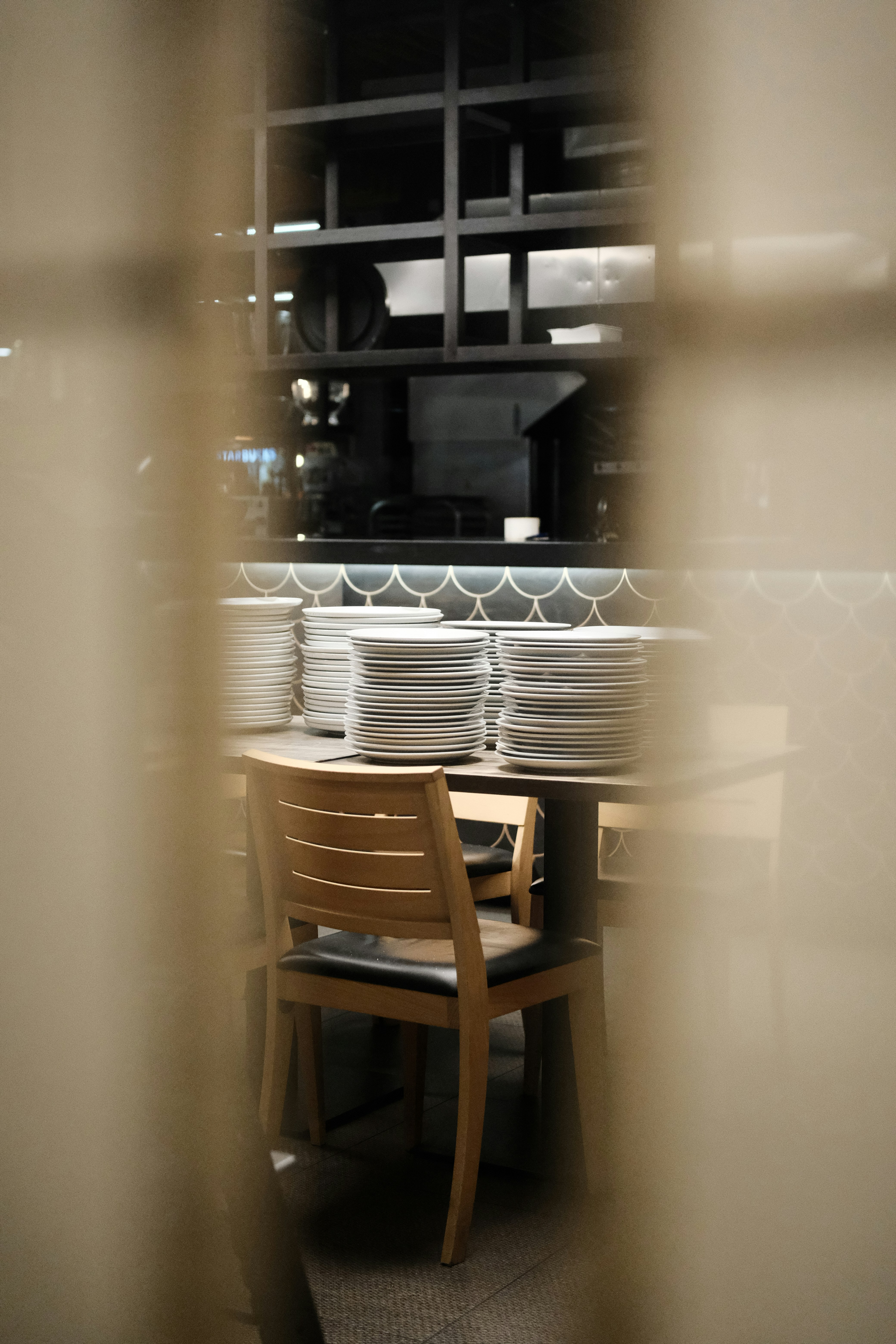 Stacks of white plates on a table with chairs.