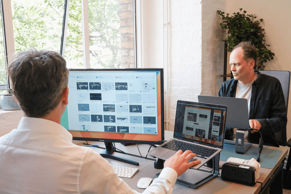 Four diverse professionals collaboratively working on a laptop, with one person pointing at the screen while others observe.