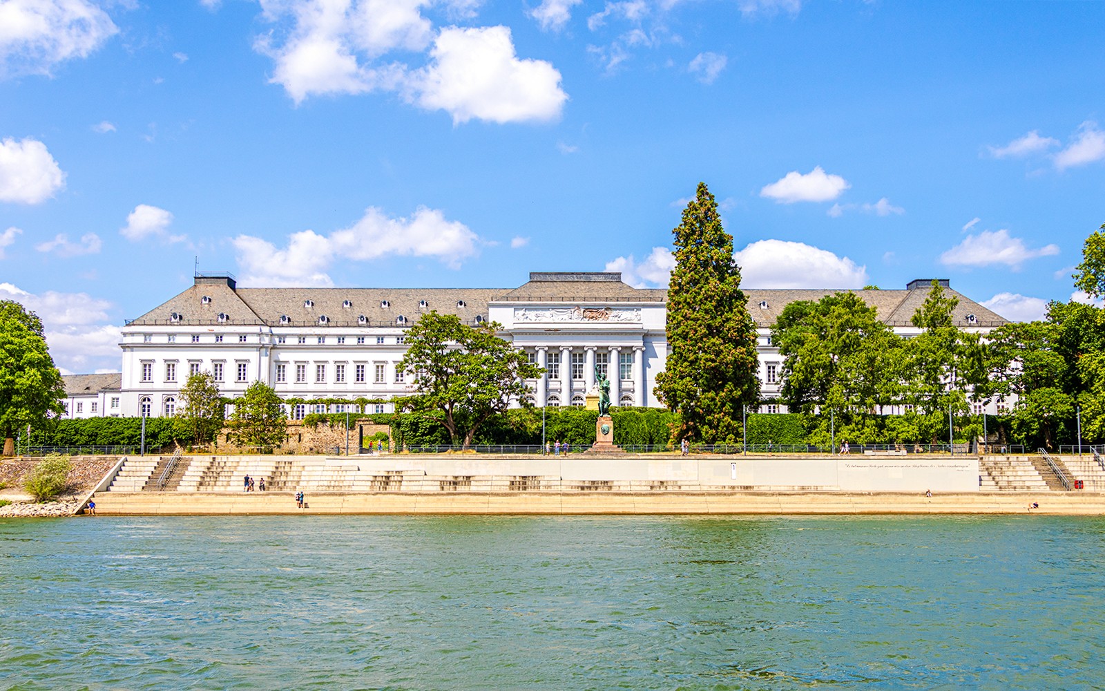 Electoral Palace in Koblenz with riverfront view and surrounding greenery.