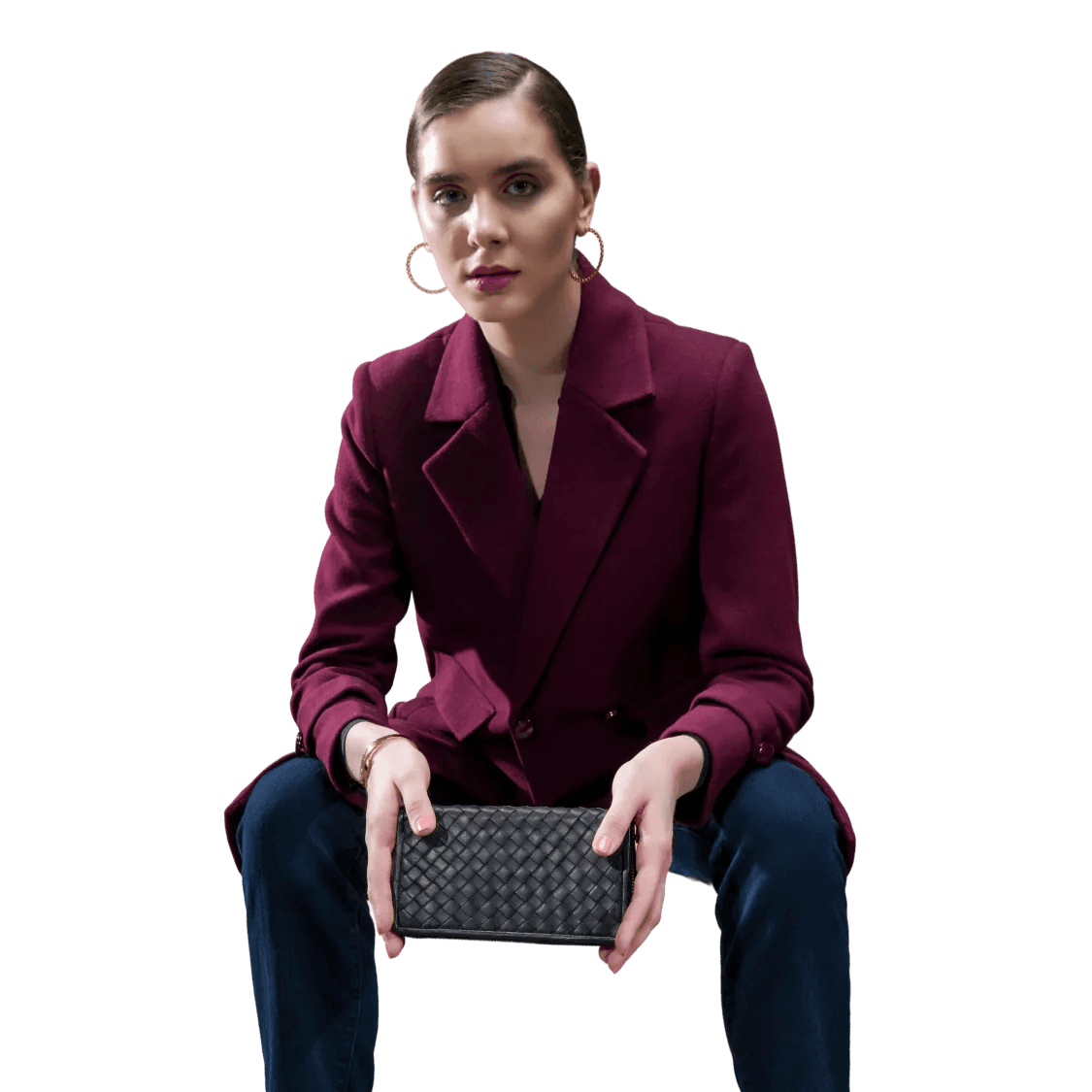 Woman in a coat holding a black textured clutch against a white background