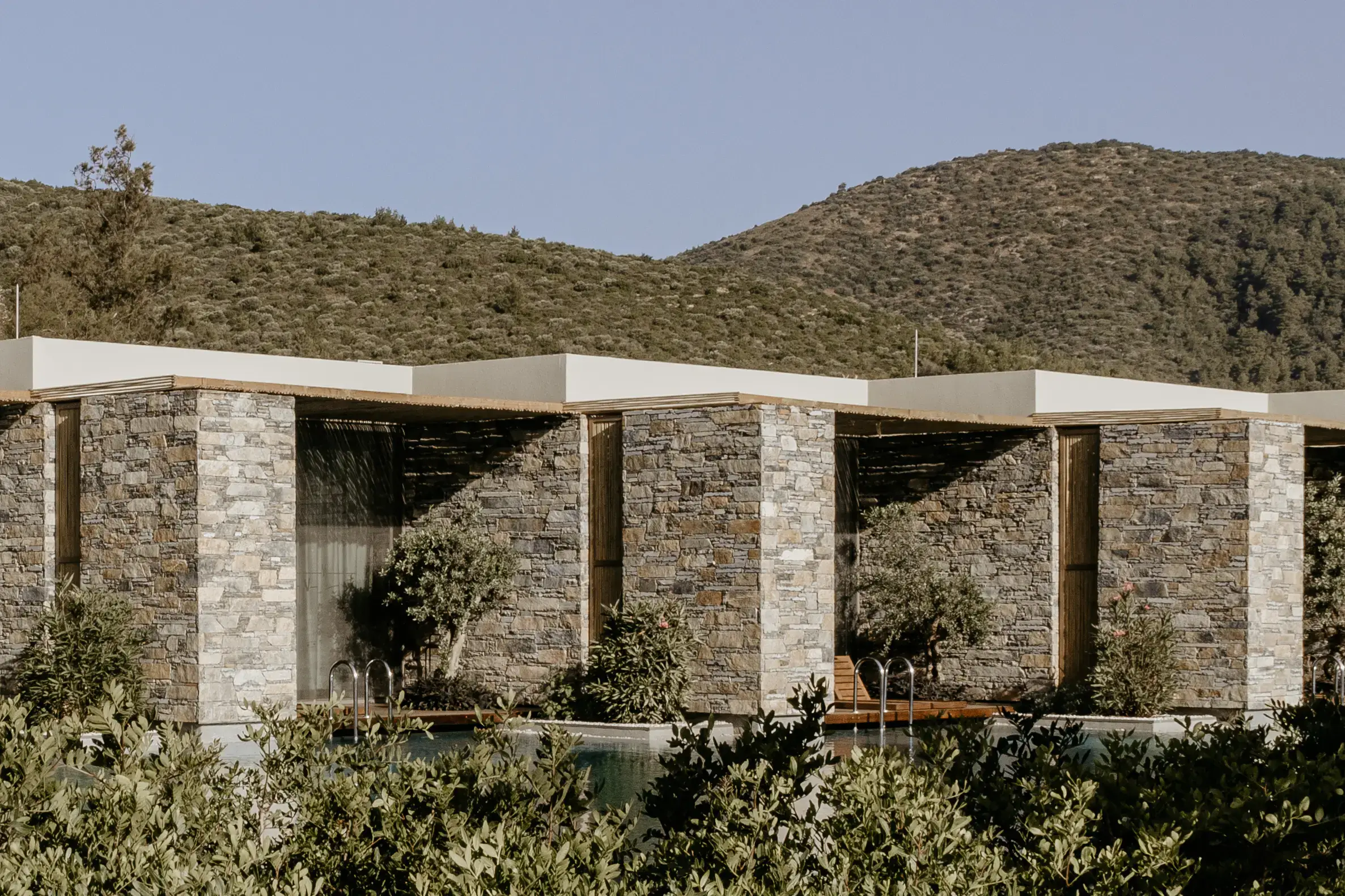 Stone-walled rooms with planting at the foot of the hill