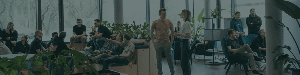 Eine Szene in einer Bürolounge in der viele Menschen sitzen sich unterhalten und an einer Konsole spielen