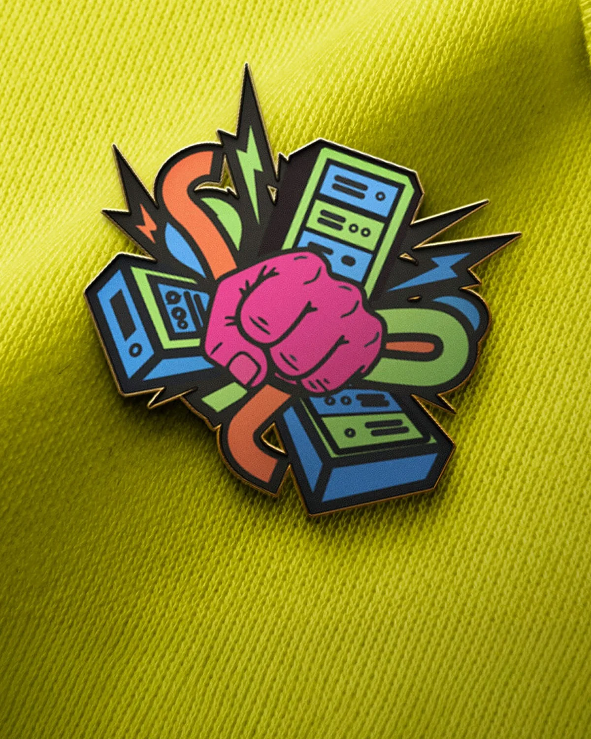 The Hum: the logo as an enamel pin, a pink fist among servers, cables and lightning, on yellow-green fabric