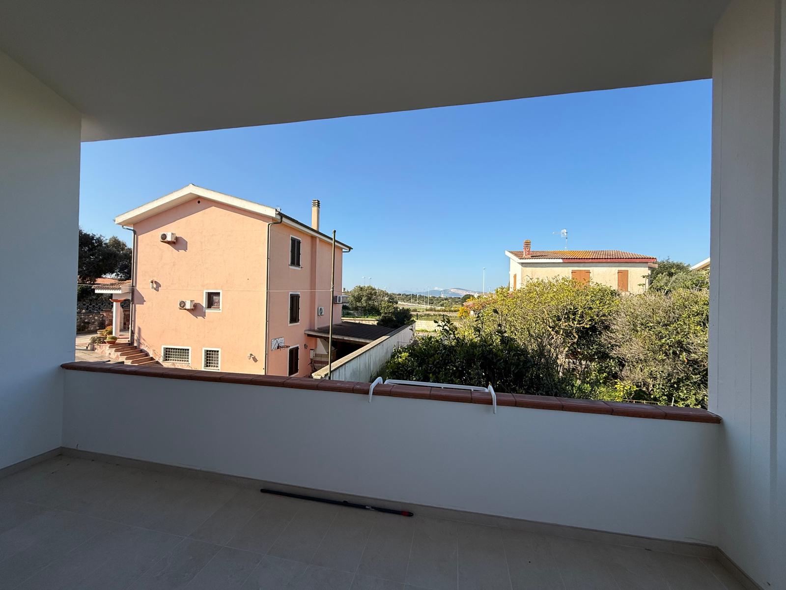 Balcone aperto prima dell'installazione della vetrata panoramica VEPA con vista sul giardino e sulle abitazioni circostanti.