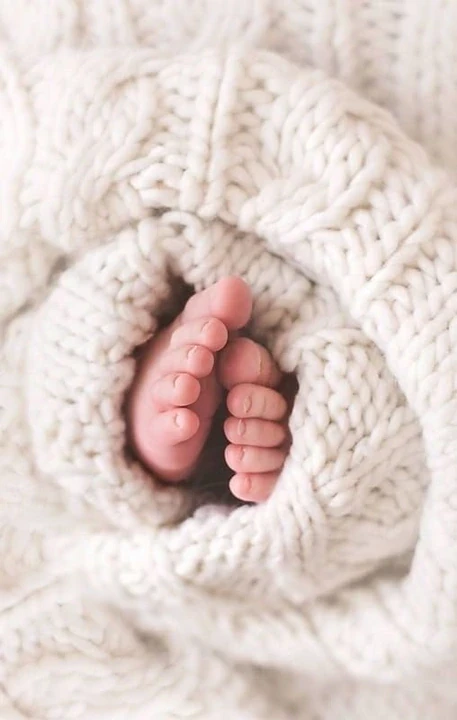 Newborn soles tucked into a cream knitted blanket