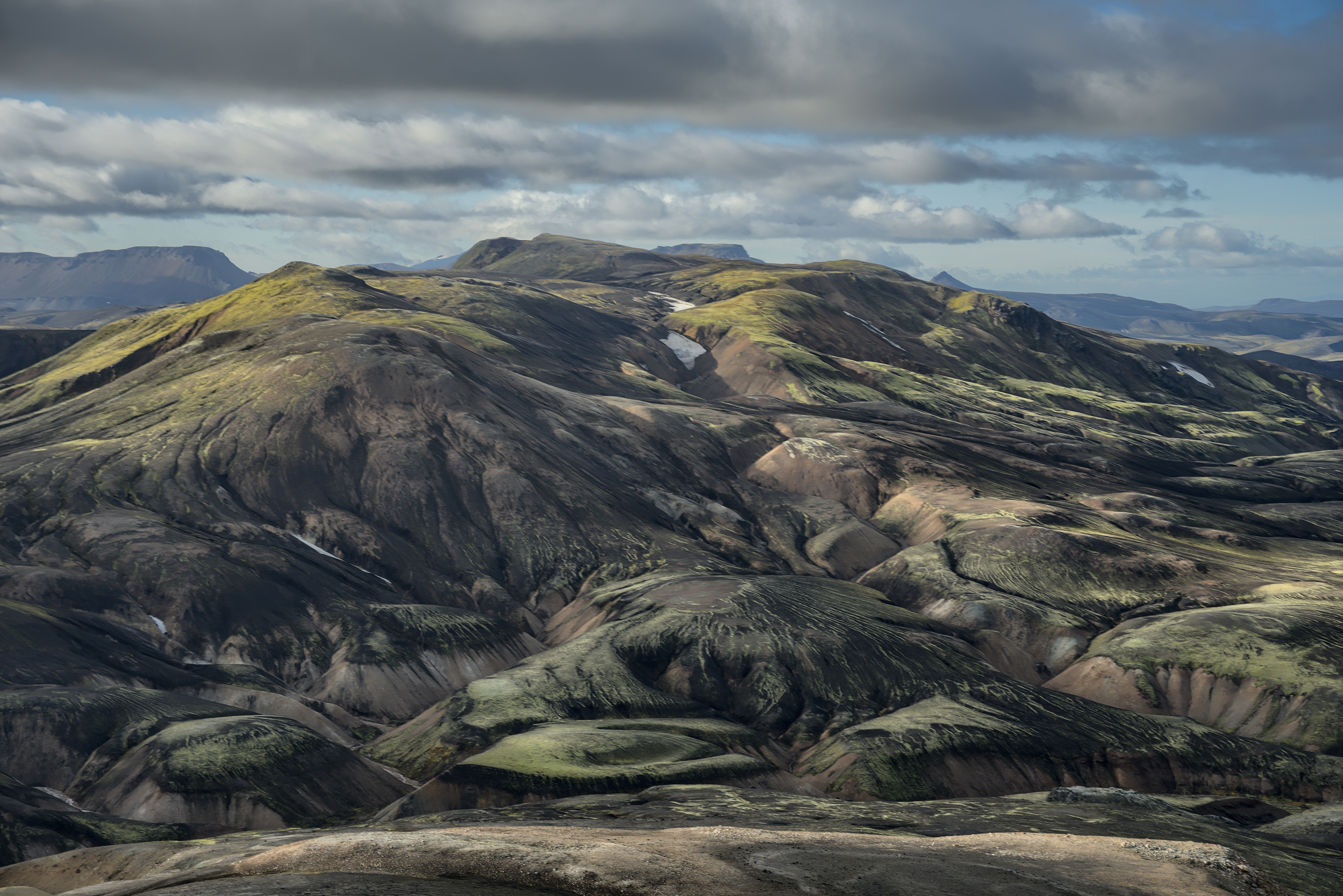 Rolling hills with patches of green moss and snow