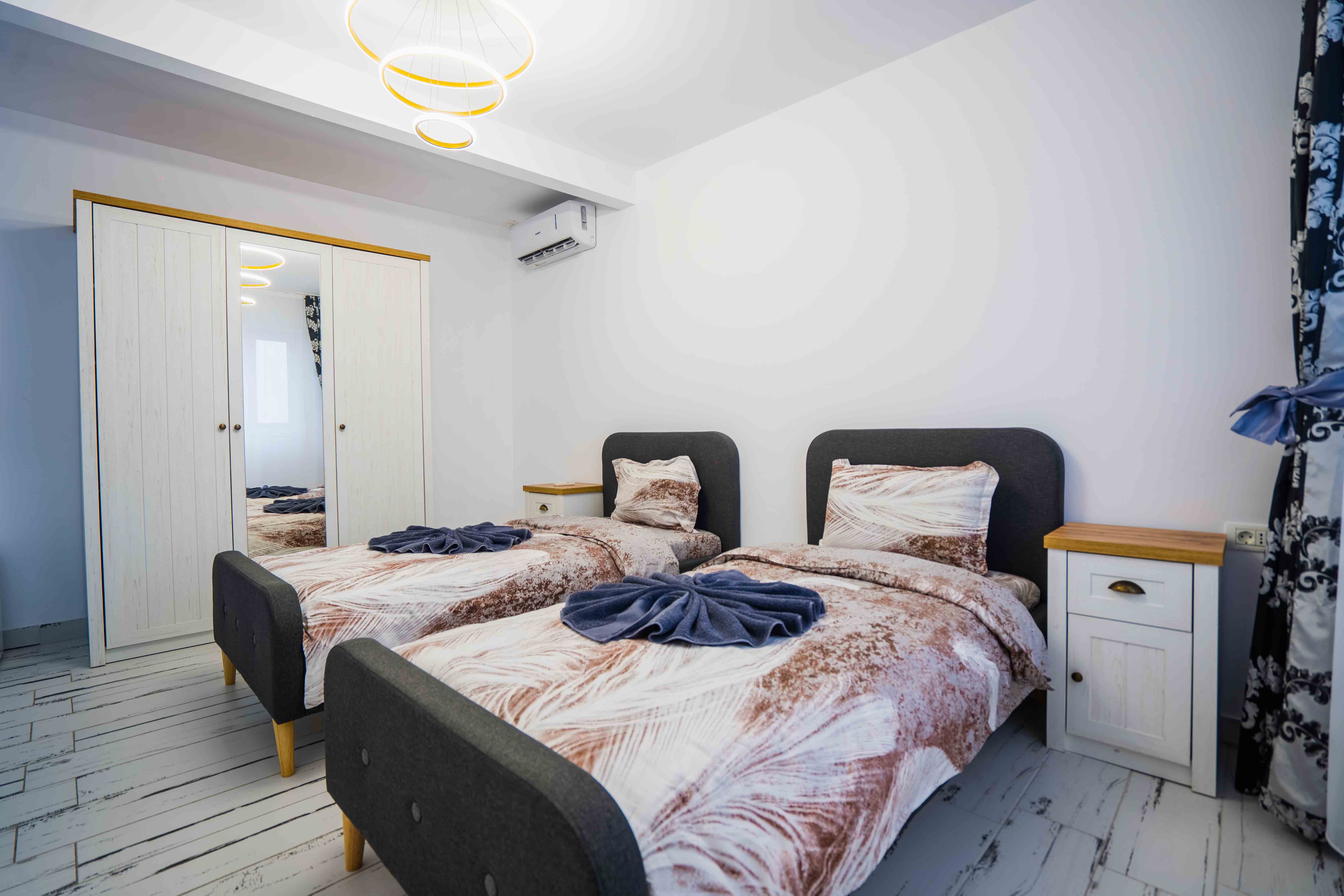 A serene outdoor lounge area with two chairs surrounded by lush greenery and natural light streaming in.