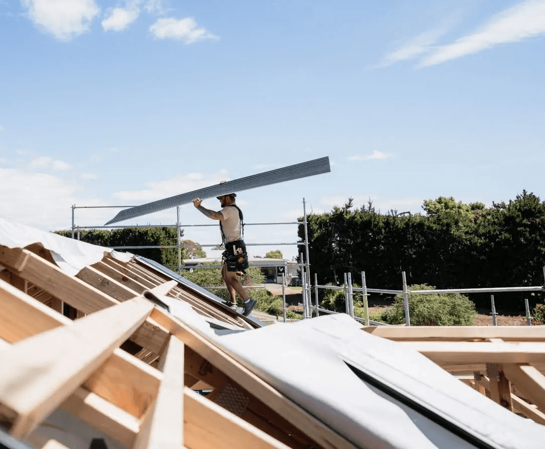 Three roof workers reviewing plans on a shingle roof.
