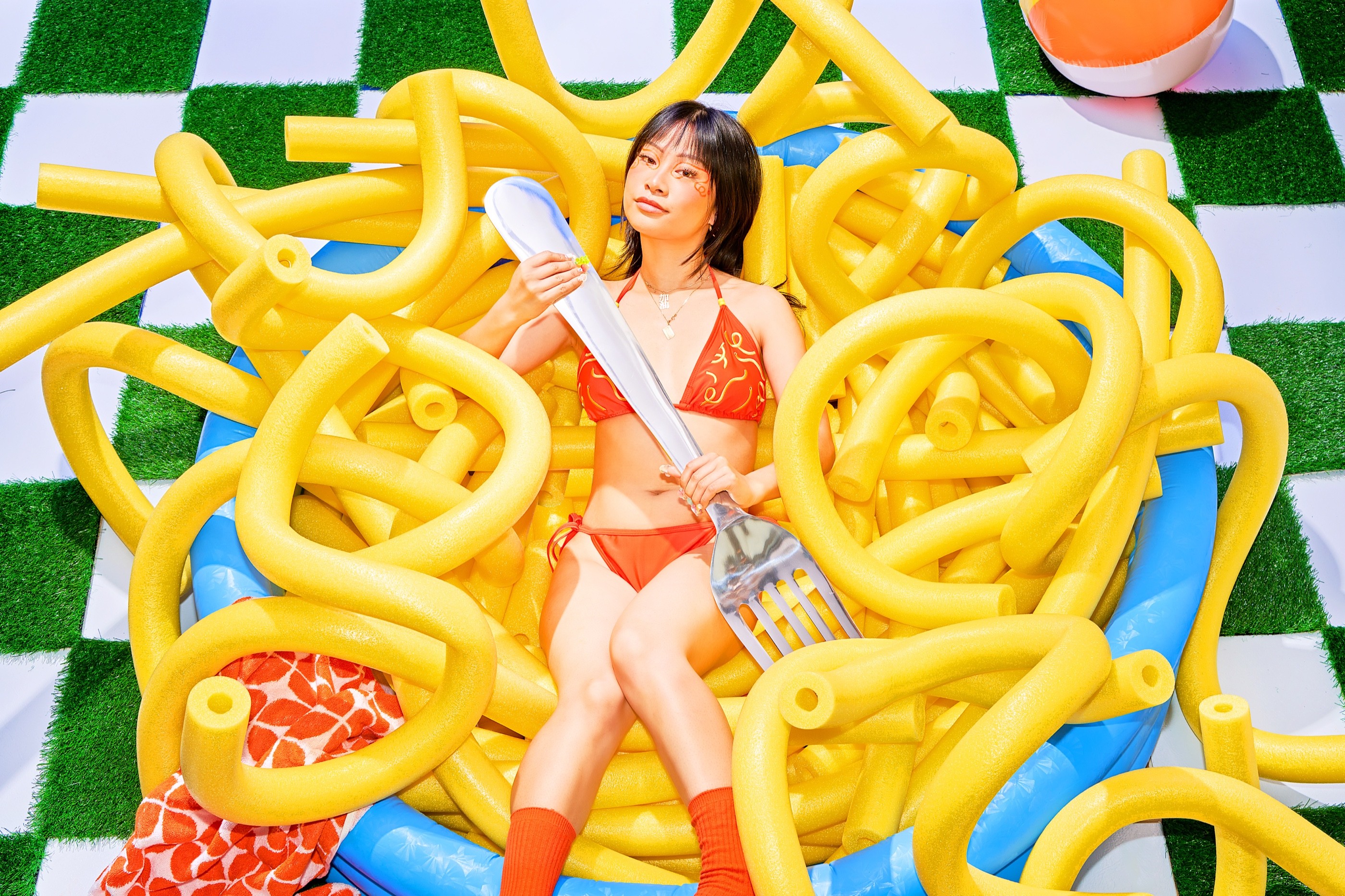 Wide portrait of Yu Ling Wu with giant yellow noodles on the Banza Bucakini set