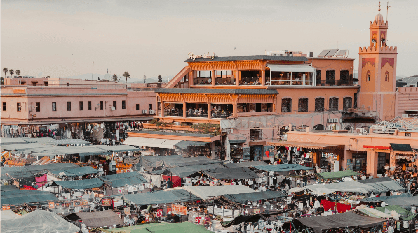 lace Jemaa el‑Fna à Marrakech, scène animée avec vendeurs, passants et stands en plein jour