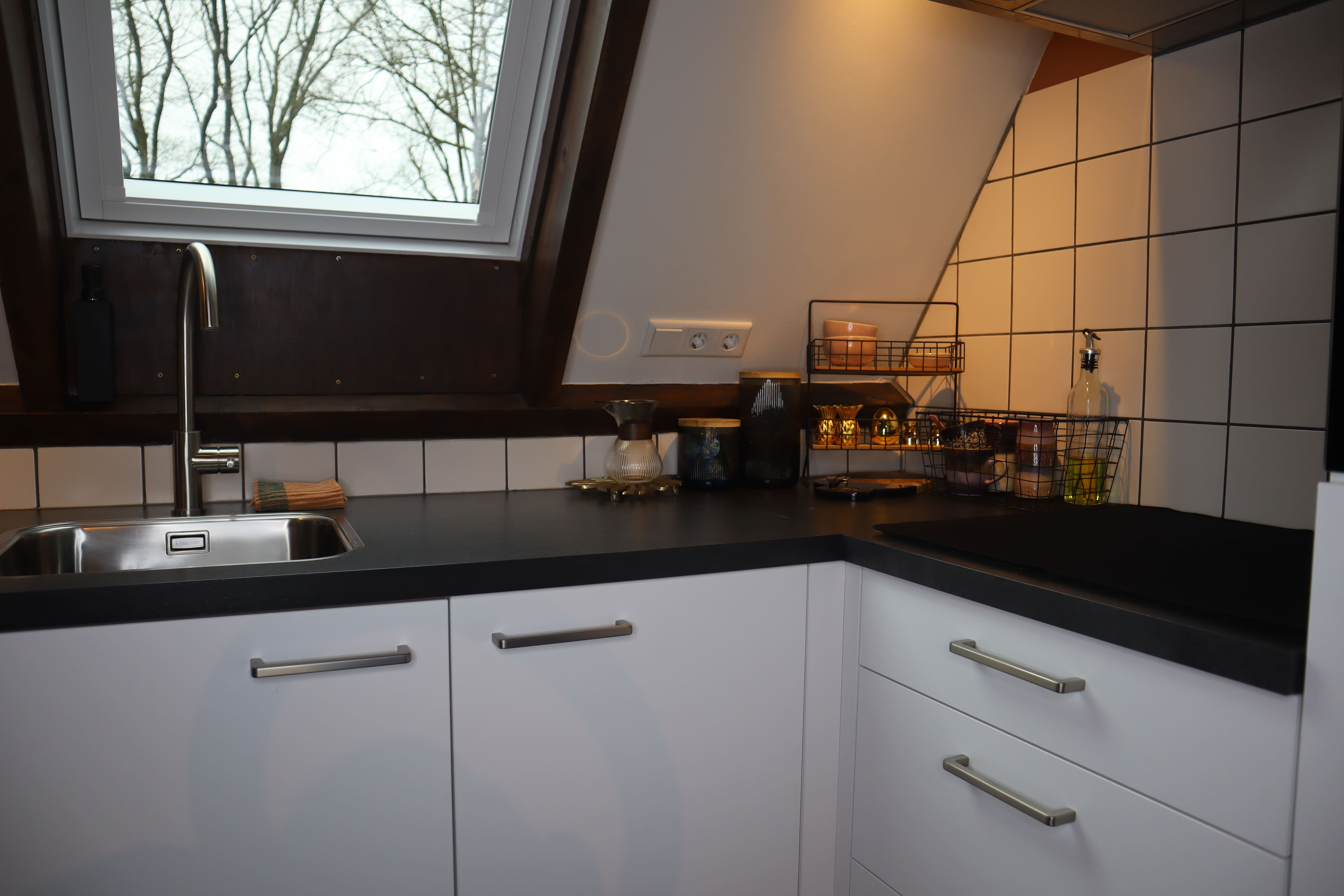 Keuken met een dakraam, witte kastjes, een oven en een koffiezetapparaat.